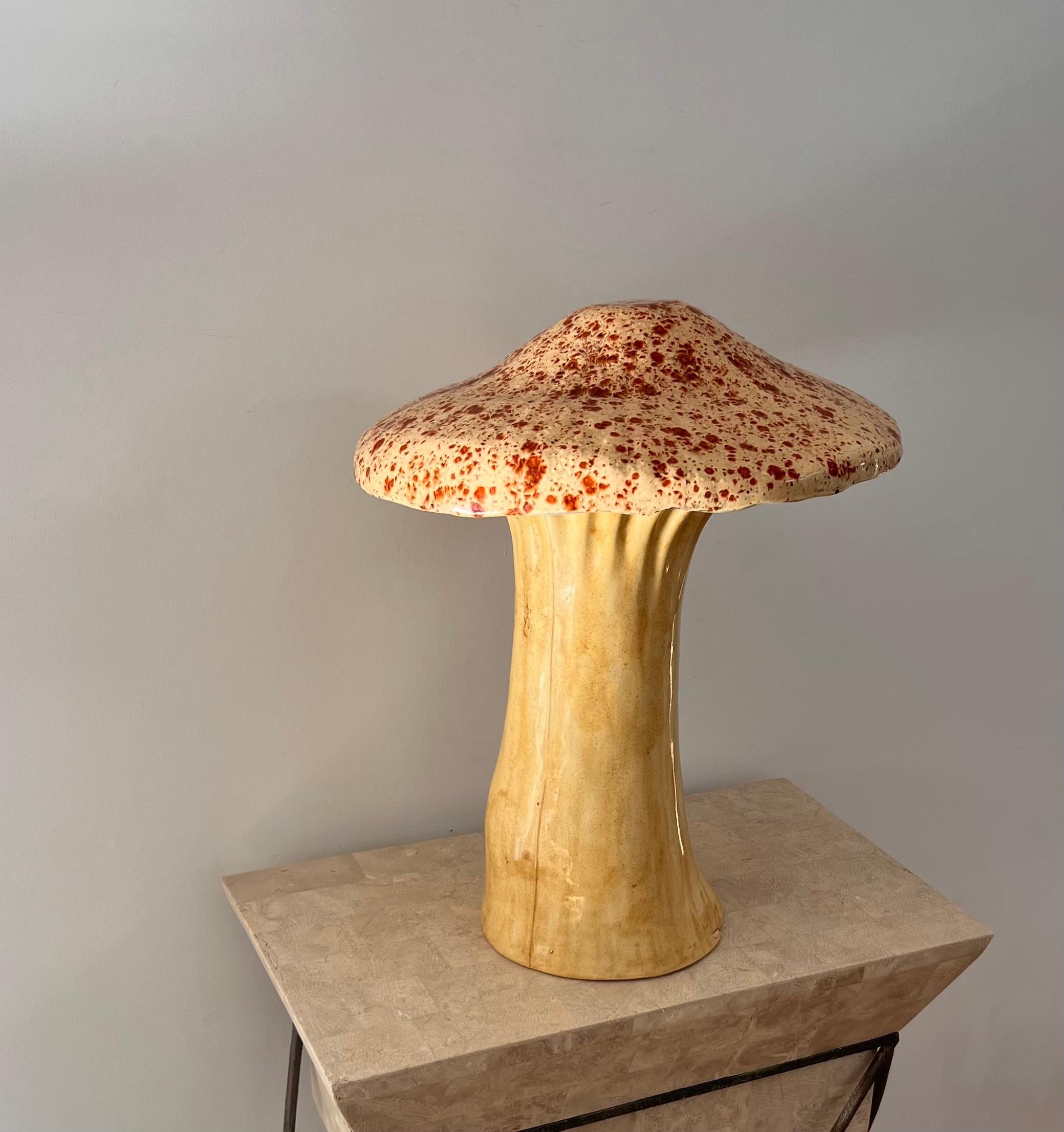 A monumental mid century modern ceramic mushroom sculpture by Arnels, circa 1960. In tones of Naples yellow and brick red, this sculpture can be displayed in a home or a garden, adding whimsy and yet sophisticated earthiness to any interior or