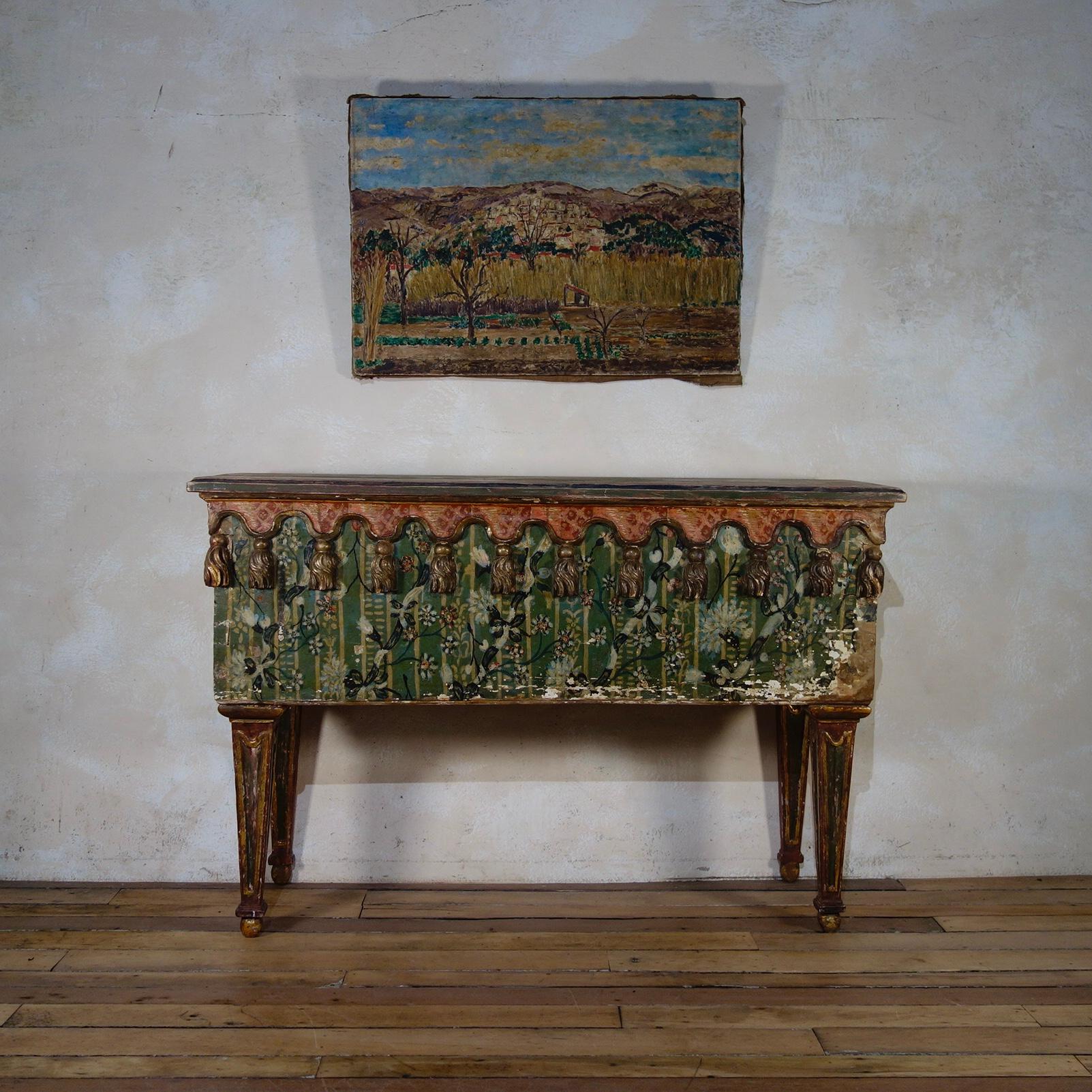 A unique and highly decorative early 19th century Italian original painted console table. Displaying incredibly charming faux painted fabric to the top and body with further carved gilded tassels to the body. Raised on tapering legs terminating on