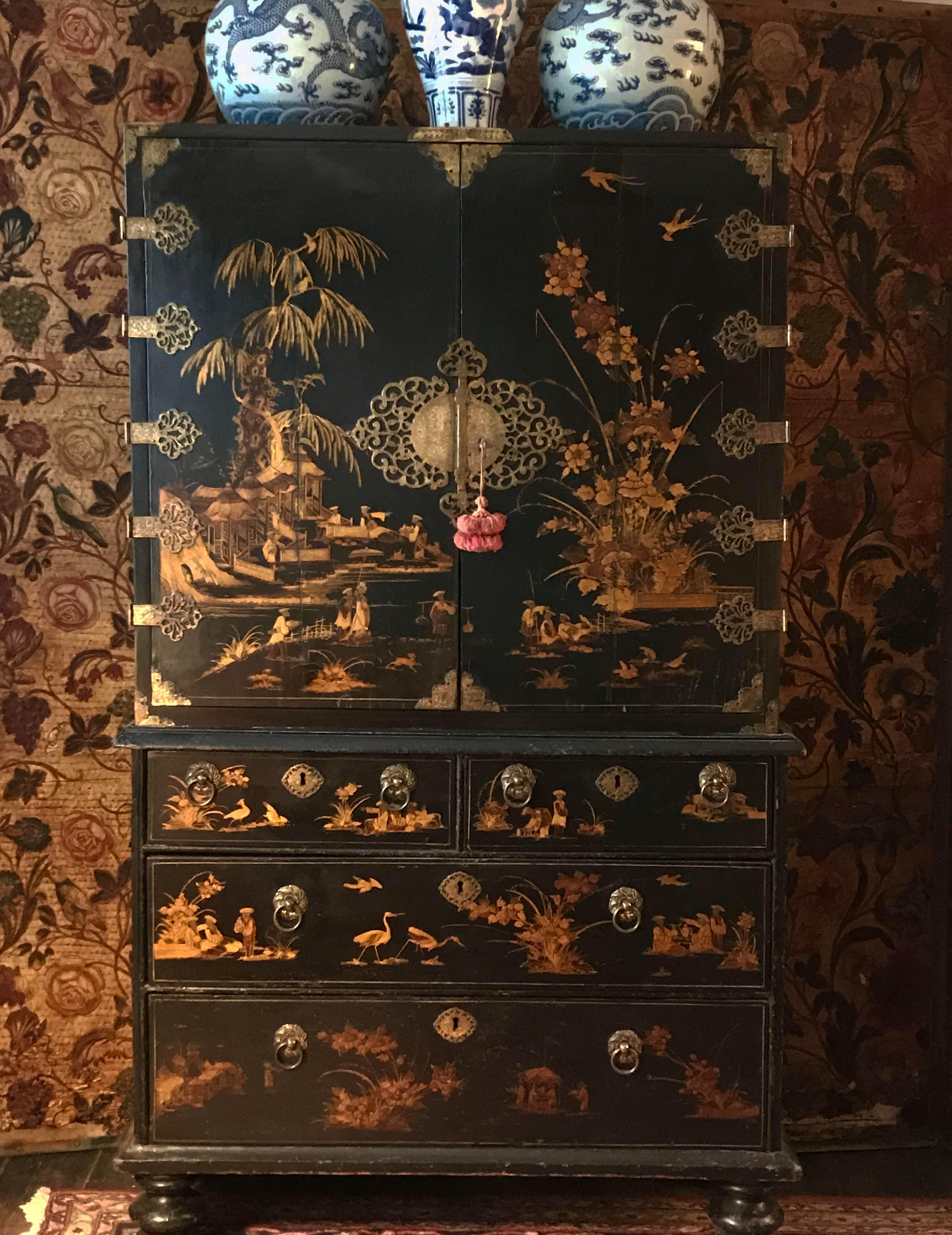 An exceptional English japanned / lacquer cabinet. William & Mary period, ca. 1690.

The top section having doors with finely engraved shaped filigree gilt hinges and lock plates, enclosing an arrangement of fitted drawers. The base with two short