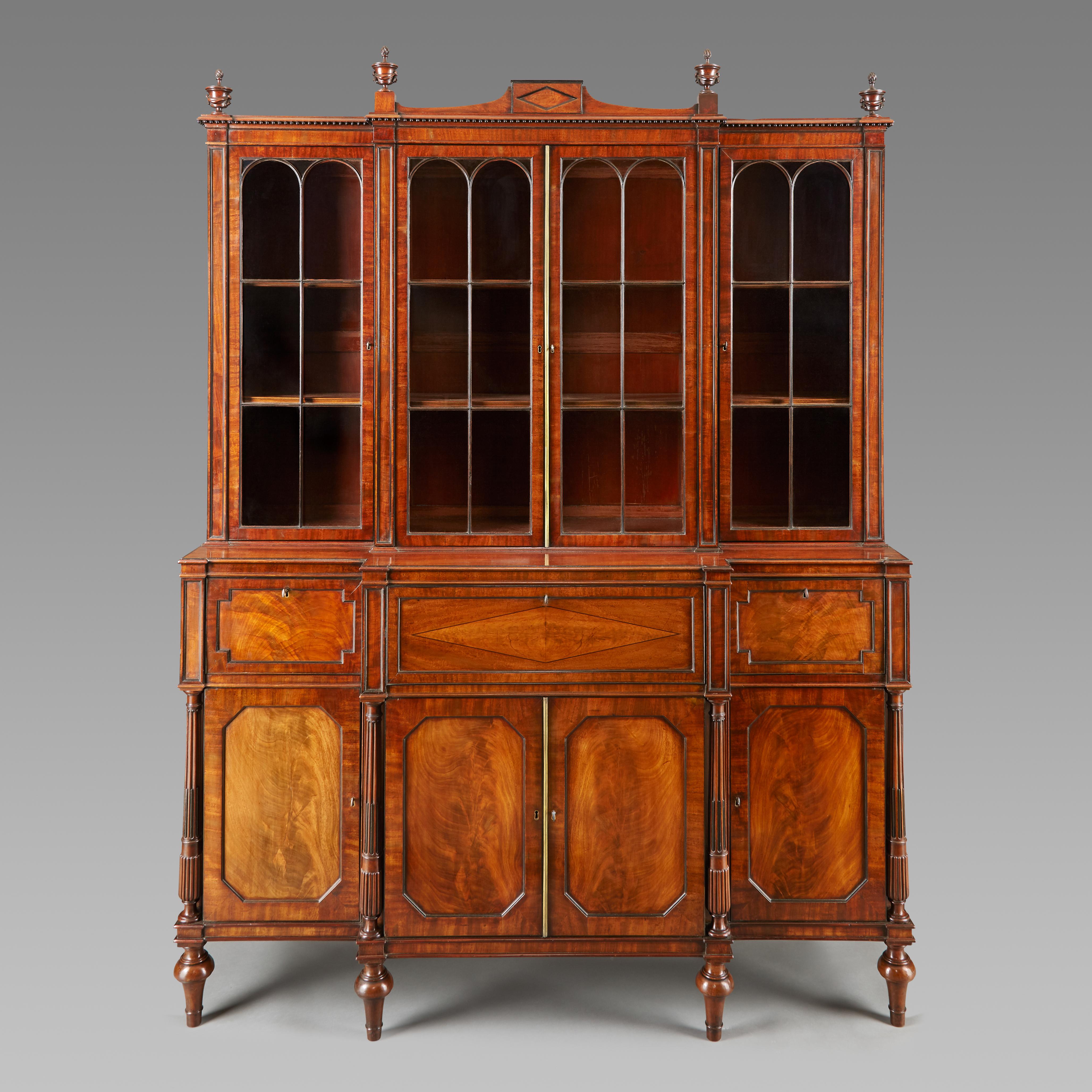 An Exceptional George III Period mahogany bookcase of small proportions attributed to Gillows. Raised on turned feet above which are stop fluted and reeded columns. The panel doors conceal shelved interiors and the centre drawer is fitted with a