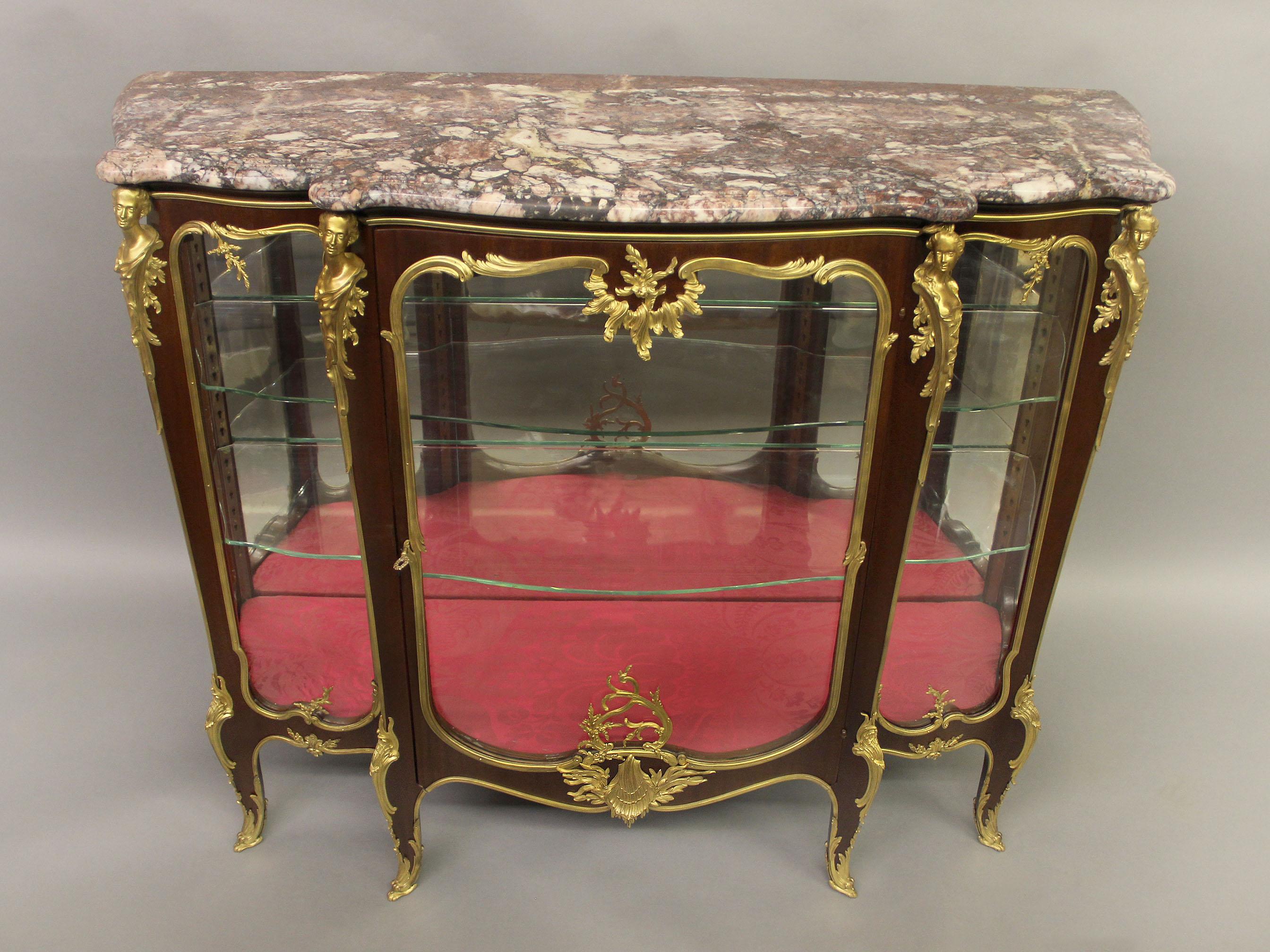 An exceptional Late 19th century Louis XV style gilt bronze mounted mahogany vitrine

By François Linke

A shaped marble top above a single central glazed door opening to a shelved interior flanked by two glass panels, the centered door with a