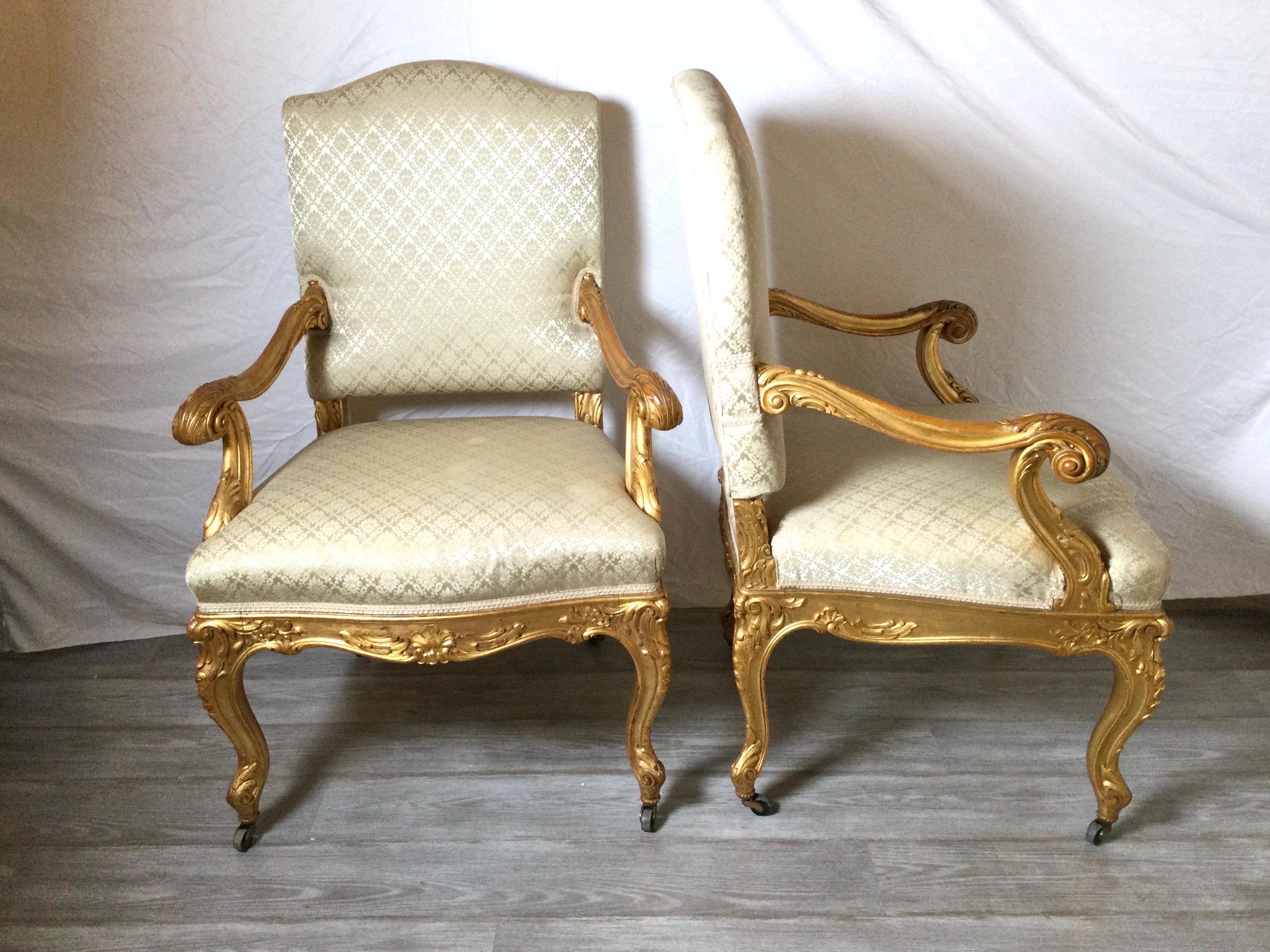 An exceptional pair of hand carved gilt framed fauteuil chairs.. The hand carved fruitwood frames with highest quality carving with gilt surface. The arms showing decades of well cared for use with jut the right amount of wood surface showing. The