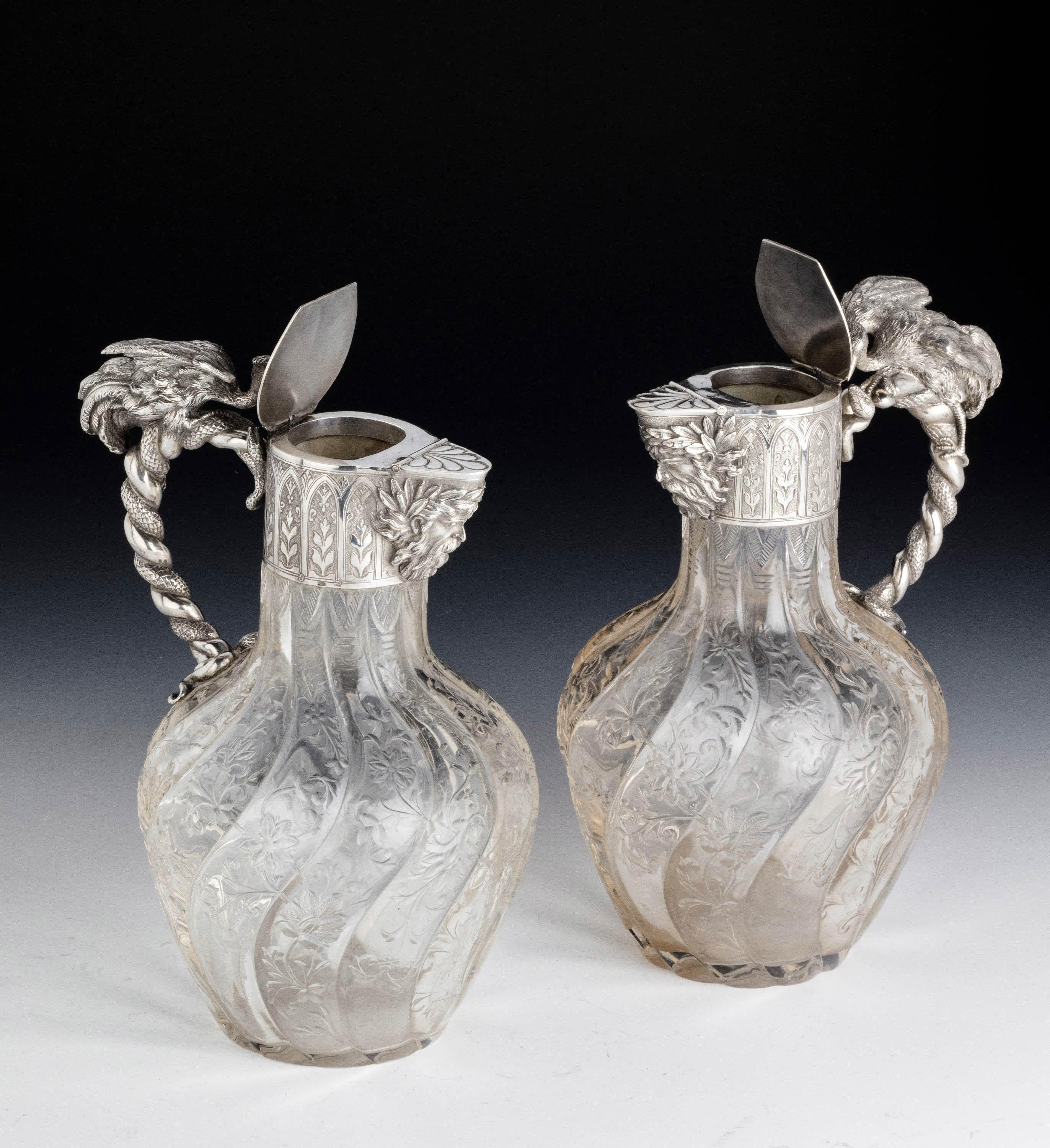 A quite exceptional pair of French silver claret jugs. The top of the handles beautifully cast and chiselled with cranes. The hinge lifting lid over a Bacchus head. The writhen bodies with inactual rock crystal design carving. In exceptional