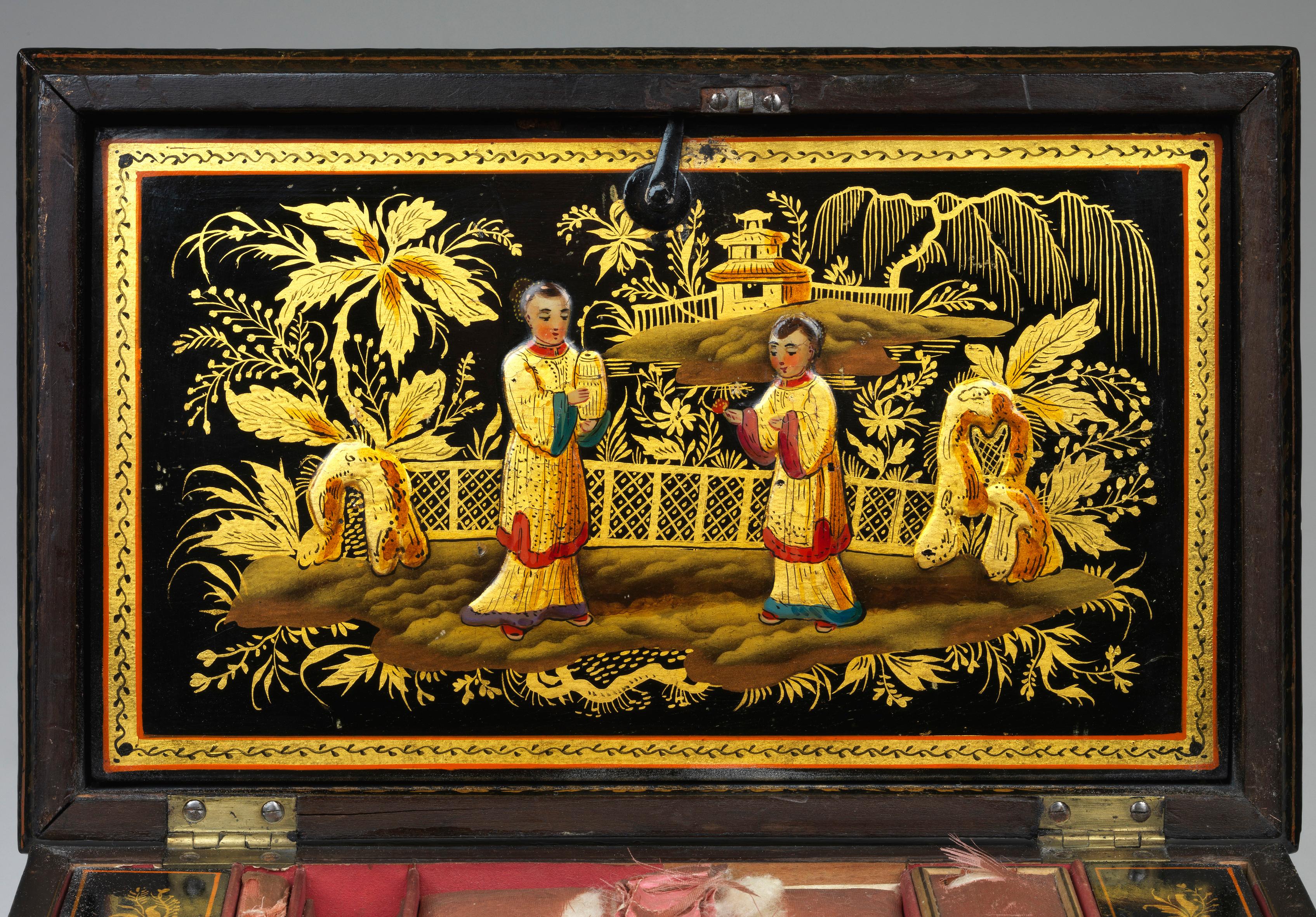 The Japanned miniature cabinet, the top having a moulded edge gilded with floral design, bordering a decorated panel with gold on black ground with Chinese figures, landscapes, buildings and trees, floral sprays and buildings and set with a wide