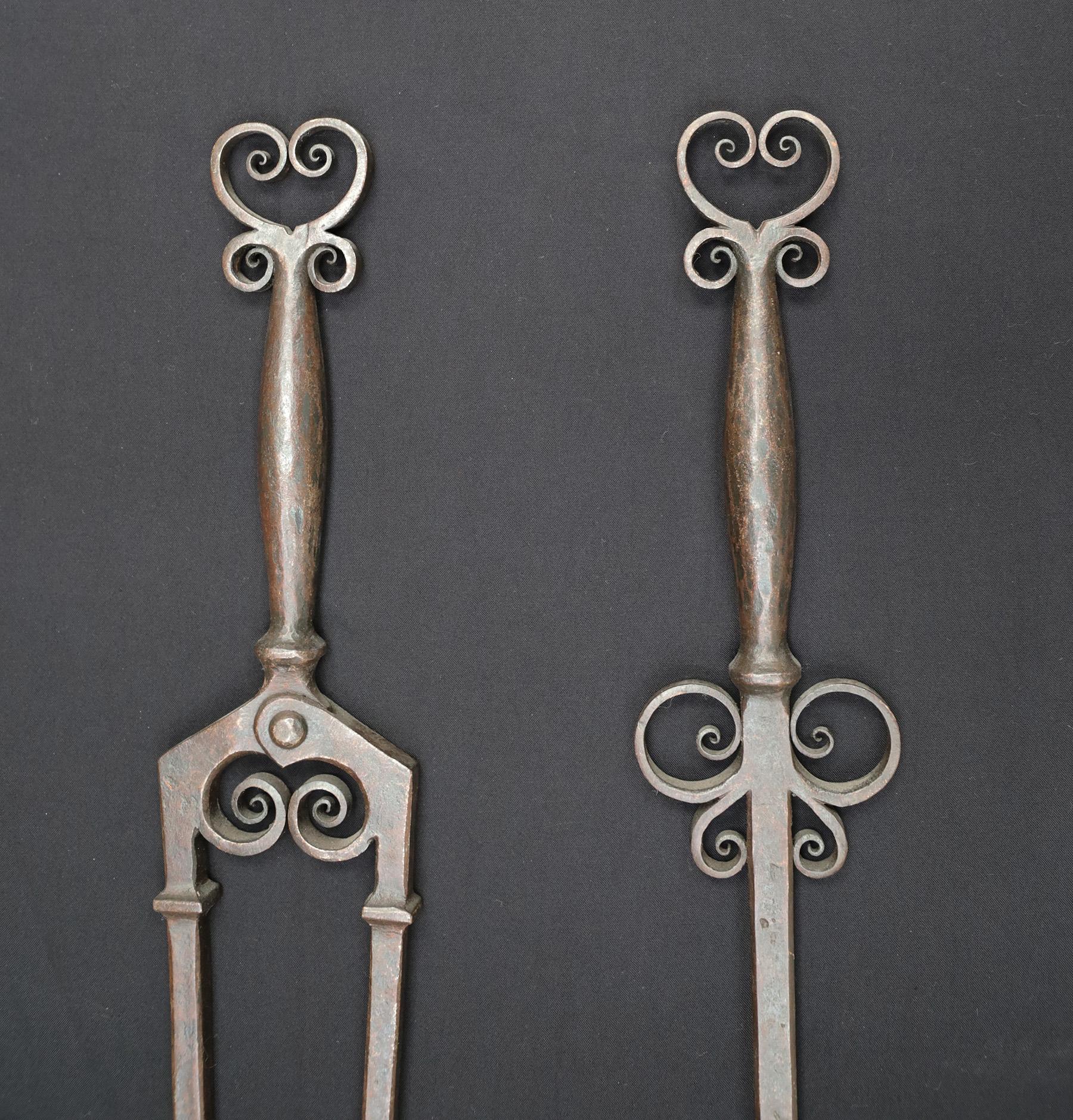 An exceptional set of Aesthetic movement wrought-iron fire tools with scrollwork. The set comprises of a set of tongs, poker and shovel. The handles with carefully scrolled finials, scroll-work to shafts, spear detail to poker end and heart-shaped