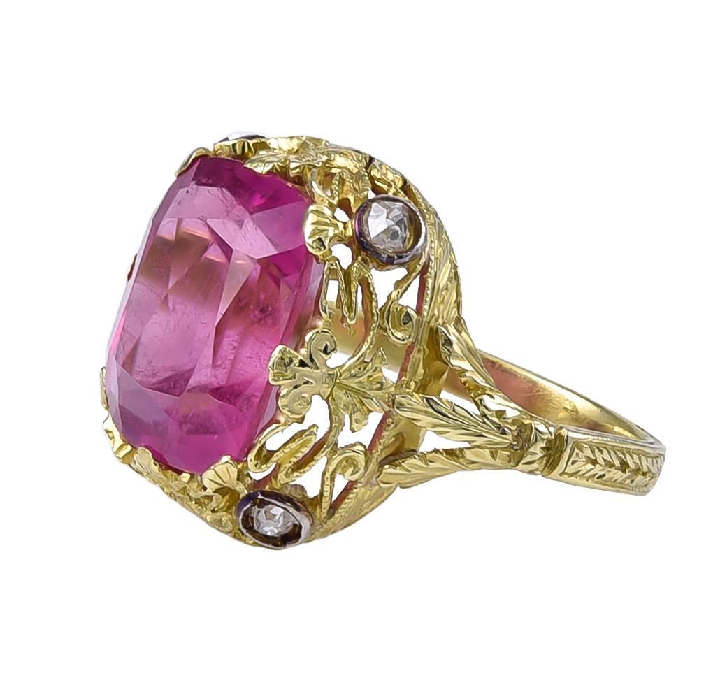 The vibrant Tourmaline, weighting approximately 4 carats, is set in an intricate Rococo style mount with 4 Silver set Diamonds at the corners and Fleur de Lys prongs holding the Tourmaline. The Ring has an ornate gallery with triple Acanthus