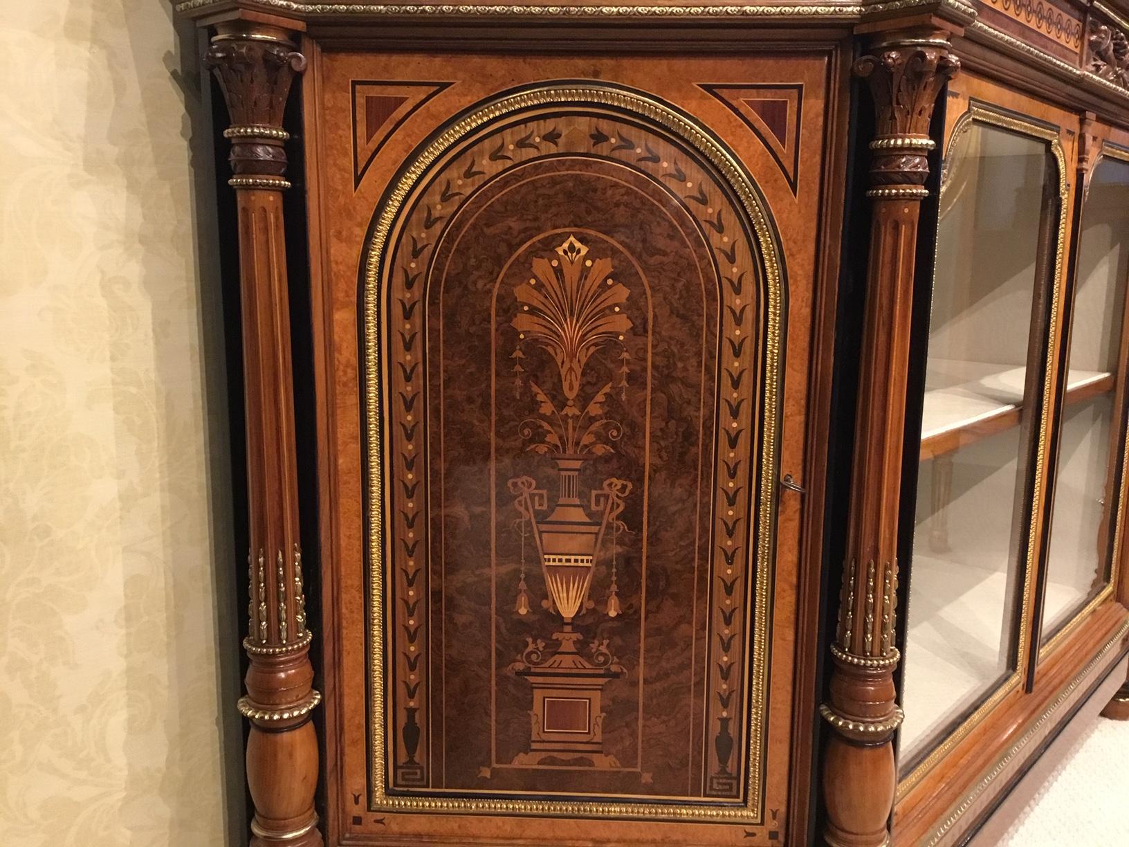 An exhibition quality Victorian period burr walnut, amboyna and ormolu side cabinet. Having a shaped top veneered in the finest burr walnut with amboyna and ebony banding and finely cast ormolu beading above an inlaid frieze with a central carved
