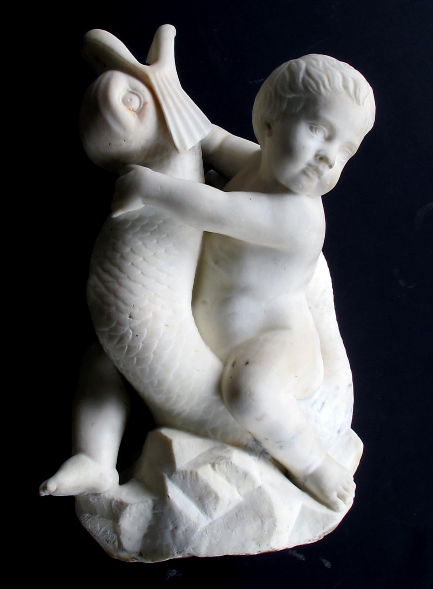 An expressive and well-carved Itallian Rococo Revival Carrara marble niche fountain of a putti seated on a dolphin; the playful chubby putti with head turned holding onto a writhing dolphin.