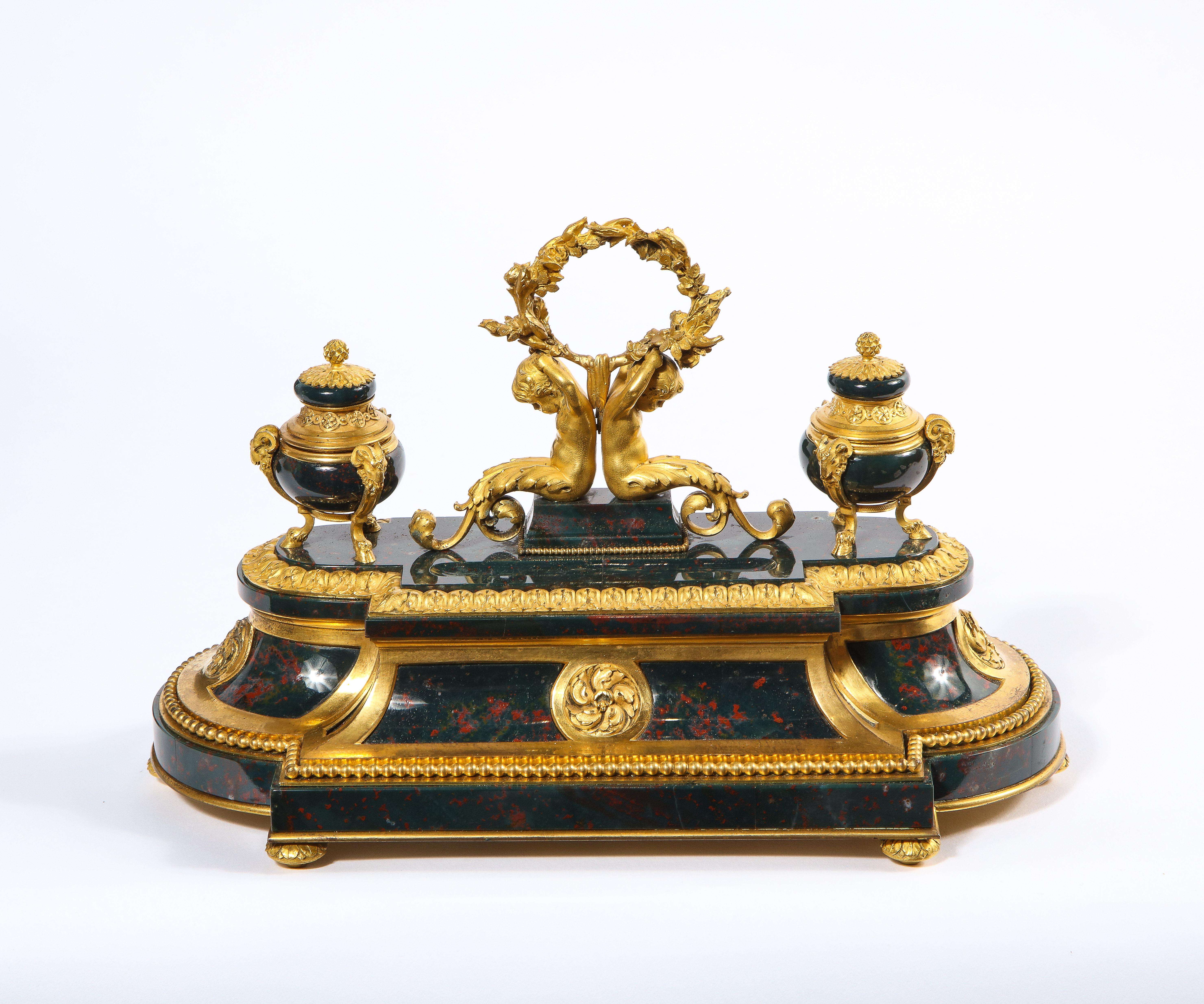 Exquis et rare encrier français de style Louis XVI en pierre sanguine montée en ormolu, vers 1875.

Un encrier en forme d'encrier vraiment exceptionnel et d'une qualité comparable à celle d'un bijou, réalisé en bronze doré de la plus haute qualité,