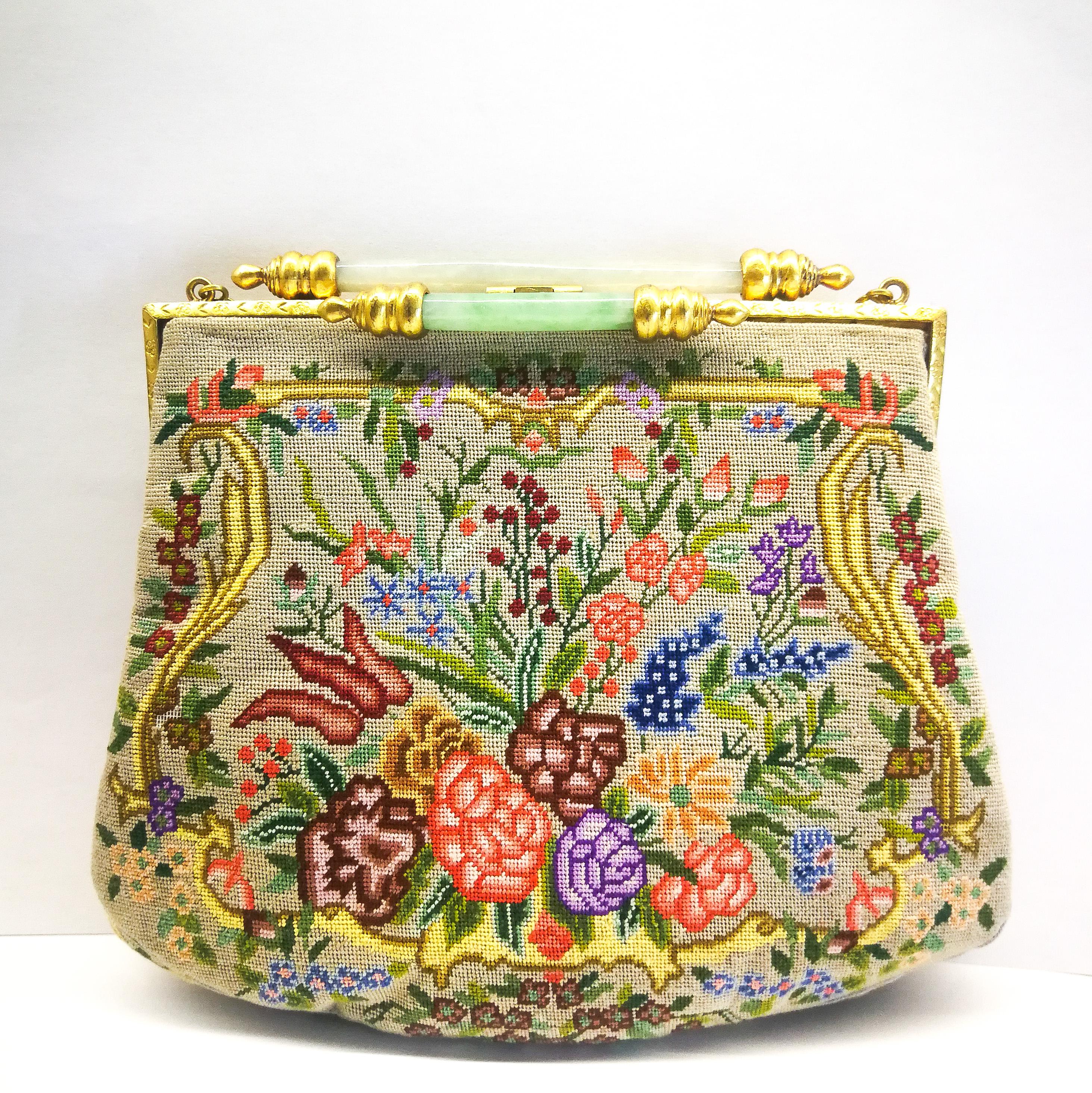 An utterly charming and striking handbag from the 1920s. The bag is in fine 'petit point' with stylised Art Deco floral motifs on both sides, in an assortment of colours , all on a soft oyster brown background, highlighted with a fine silver grey