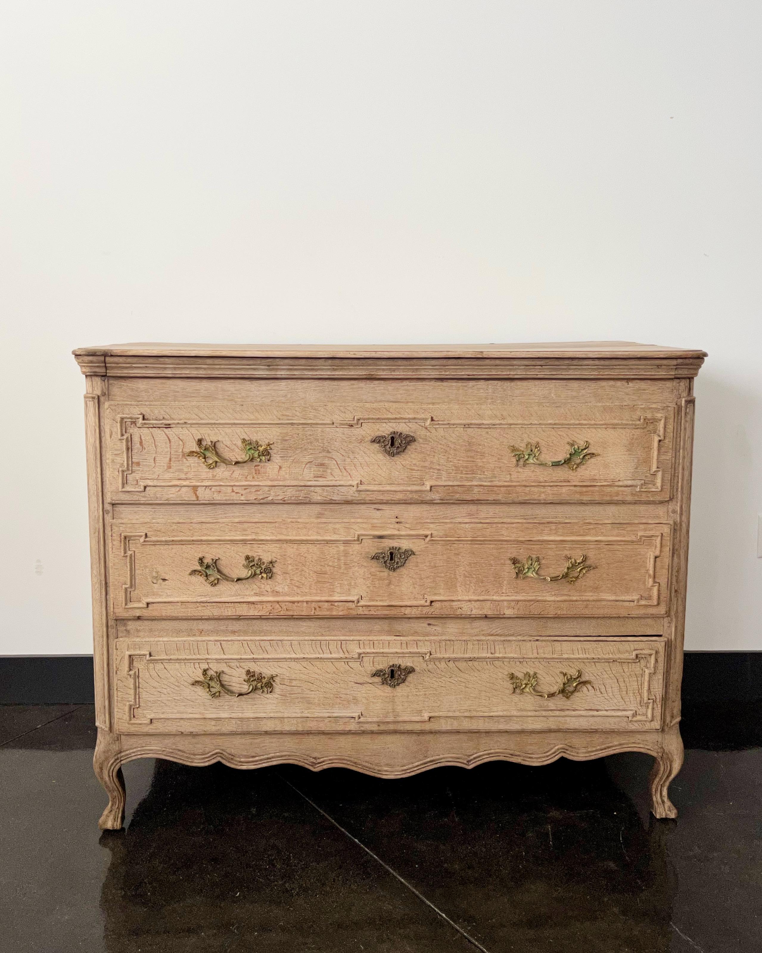 An exquisite French Louis XV/Louis XVI Transition period bleached oak commode with richly carved drawer fronts, decoratively carved apron and paneled sides and beautiful original hardware,
circa 1775.
