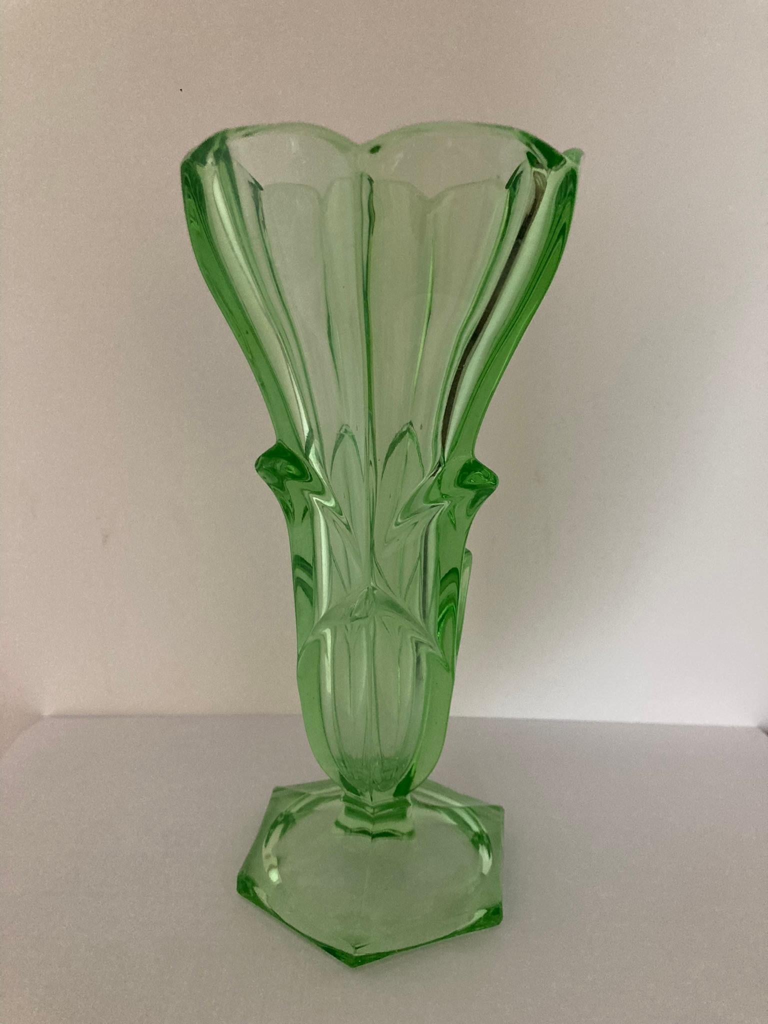 An exquisite green uranium glass vase with a captivating flower design. Crafted with precision, this elegant vase adds a touch of sophistication to any space. The vibrant green hue complements the intricate floral pattern, creating a stunning visual