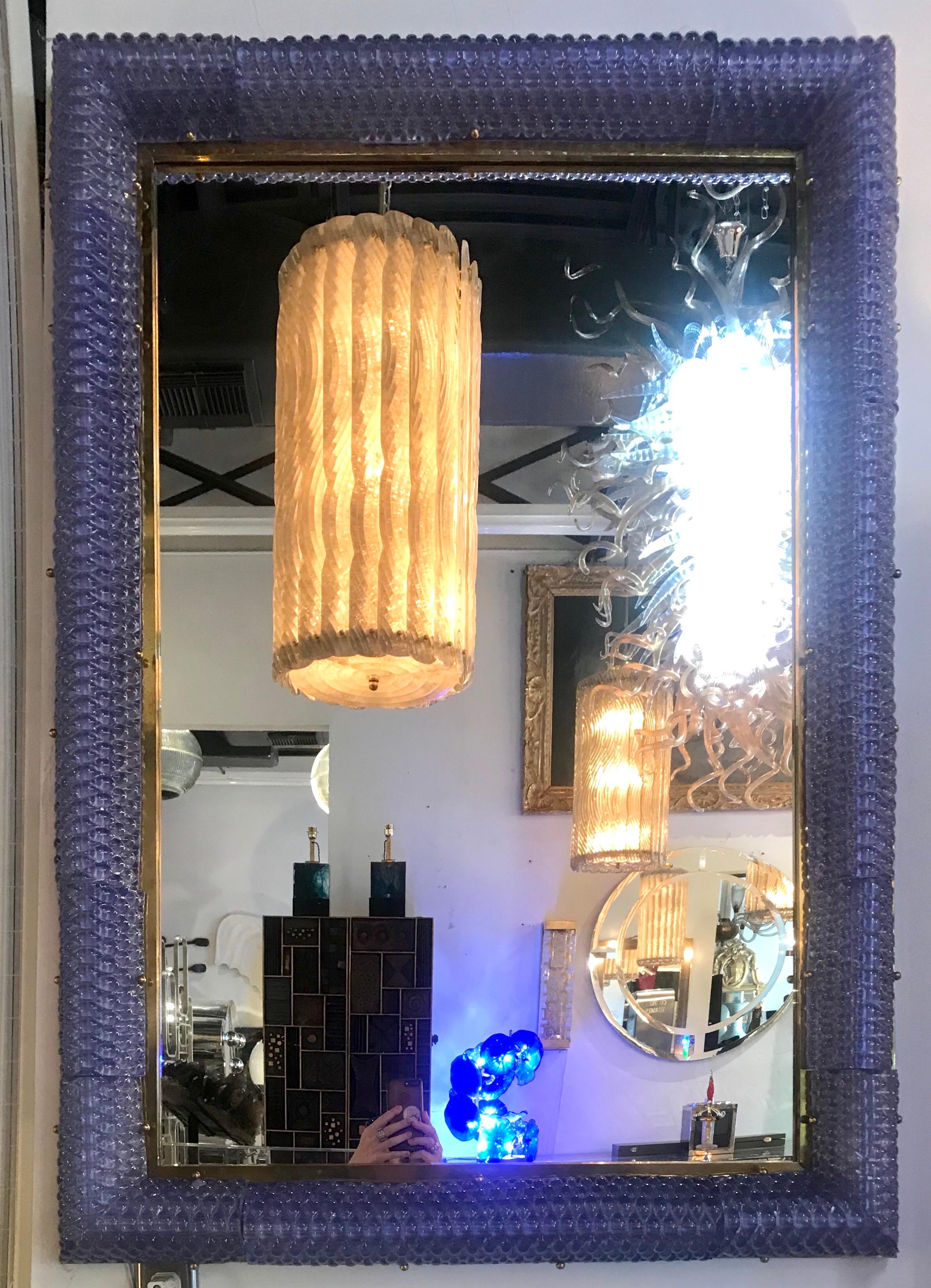This large Italian blown glass mirror is a light lavender blue with brass trim illuminates creating a gorgeous Rosie glow in it's environment. Wired for the USA.