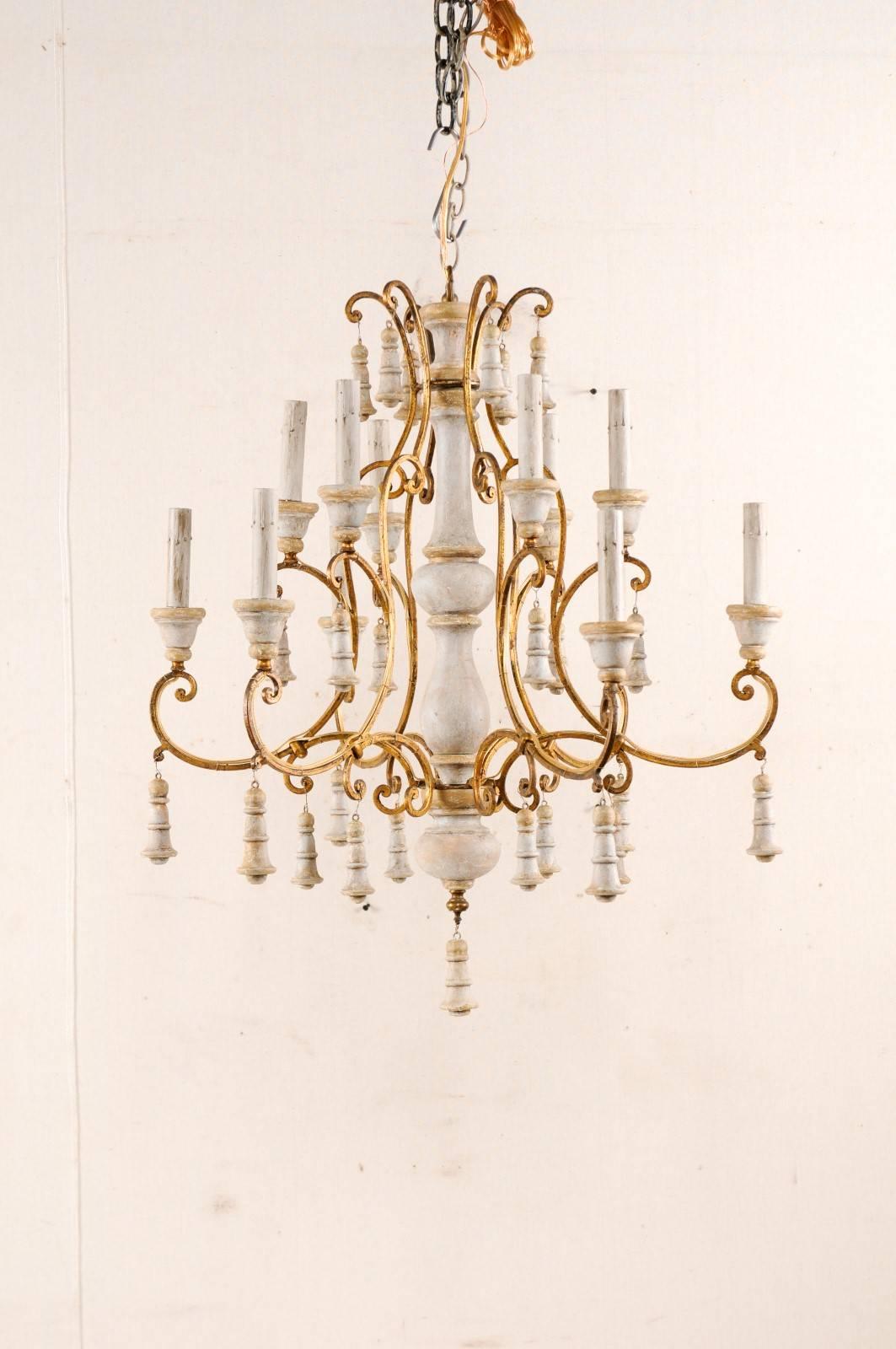 An Italian vintage two-tiered, twelve-light chandelier. This mid-20th century chandelier features a turned and painted wood central column, contrasted nicely with scrolling gilt iron armature. There are two tiers of lights, twelve lights in total,