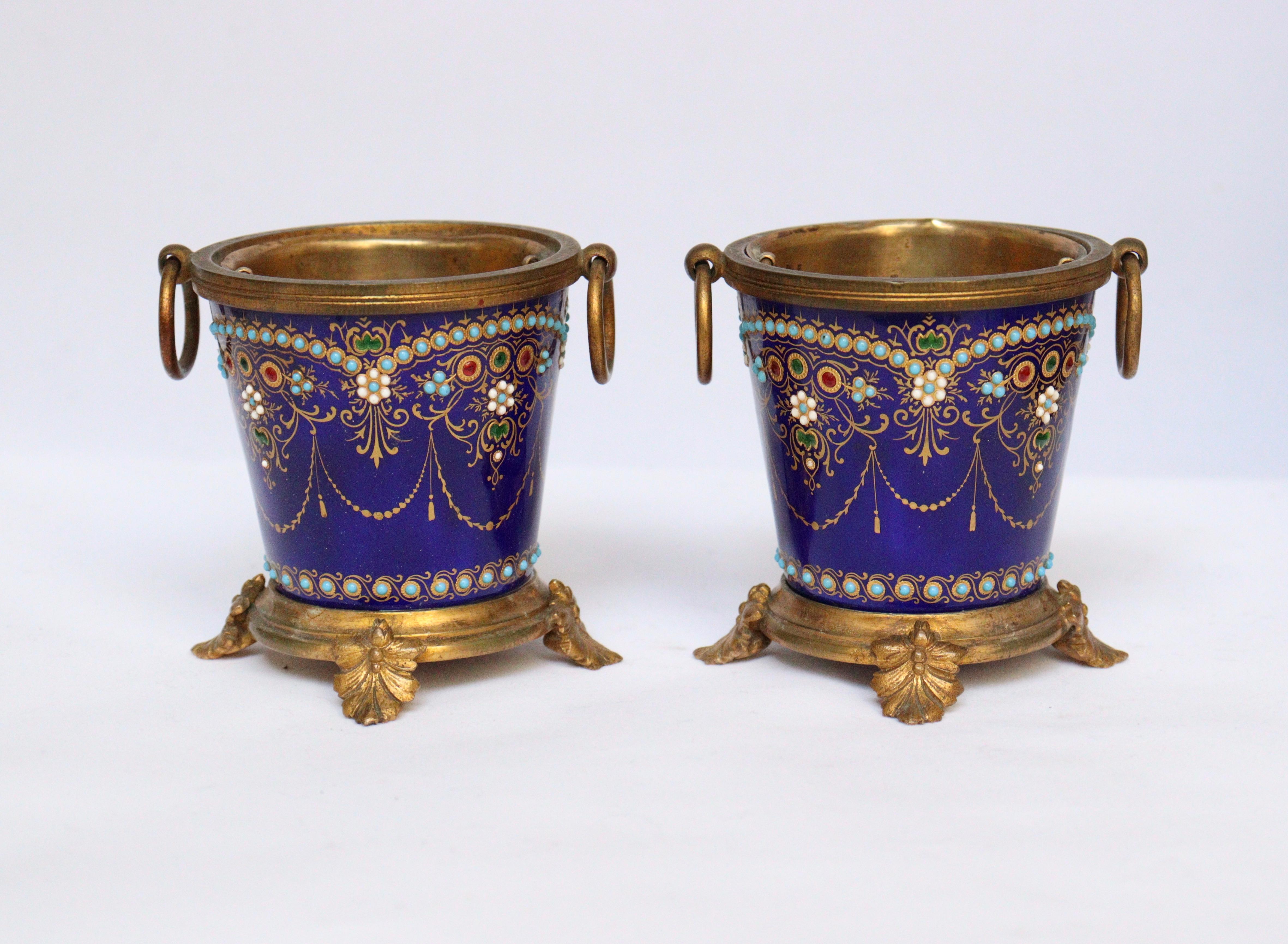 A French 19th pair of enamel and ormolu mini cache-pots
Very finely hand-painted enamel on copper designed with gold motif in arabesque on a deep blue sèvres ground, highlighted with half-pearls in white, green, red and pale blue Coteau