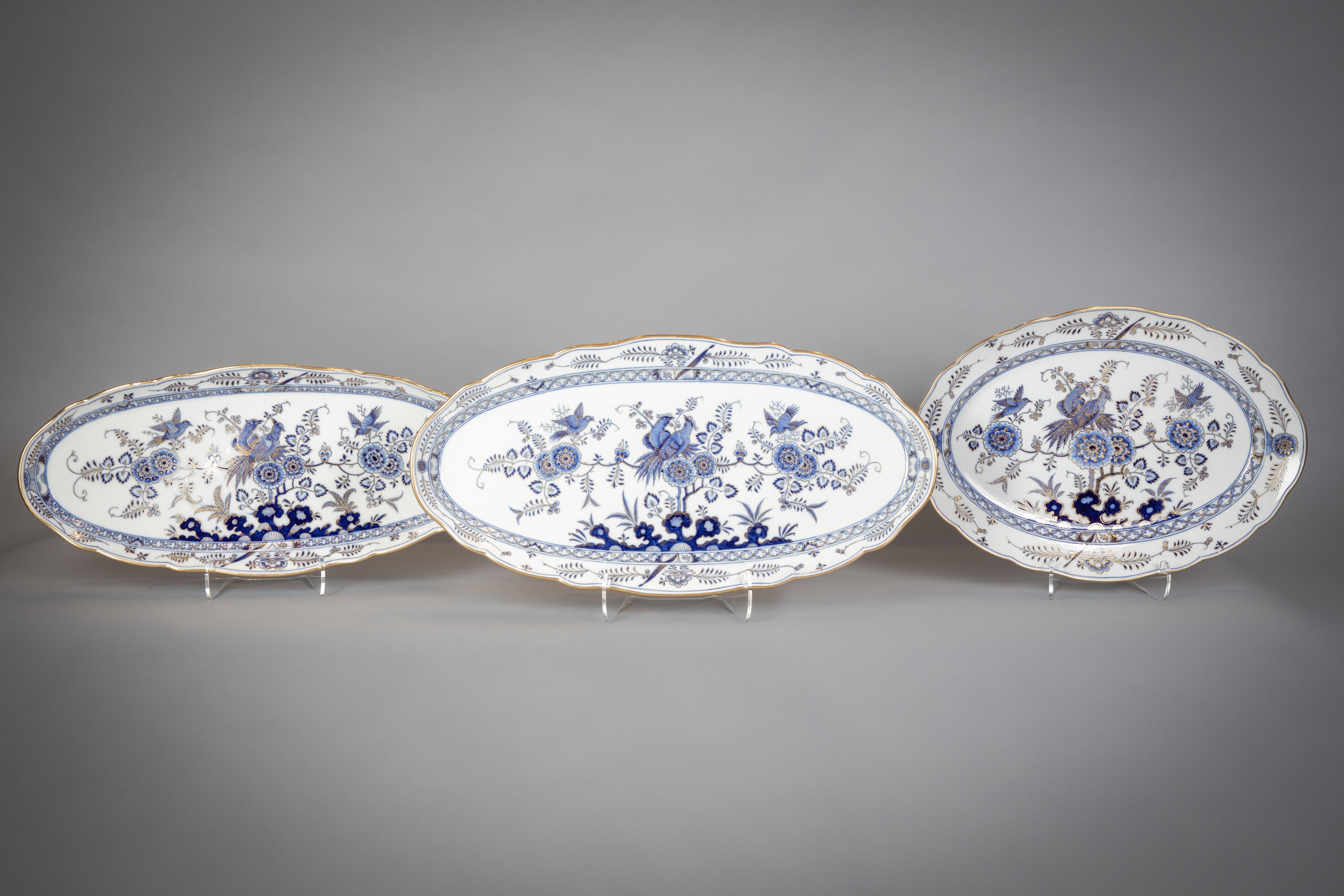 Each piece painted in underglaze-blue and heightened in gilding with an exotic bird perched upon peony branches, comprising: an oval soup tureen, cover and two stands, an 18
