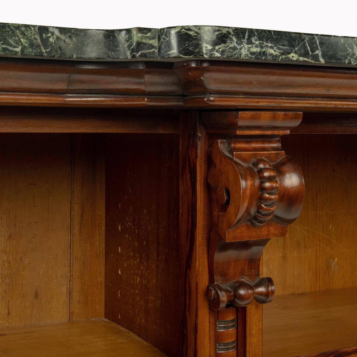 An extensive William IV Goncalo Alves breakfront open book case, the green marble top set above five open sections, each with two adjustable shelves and divided by pilasters with turned centres and scrolling corbels, the leather dust fringes