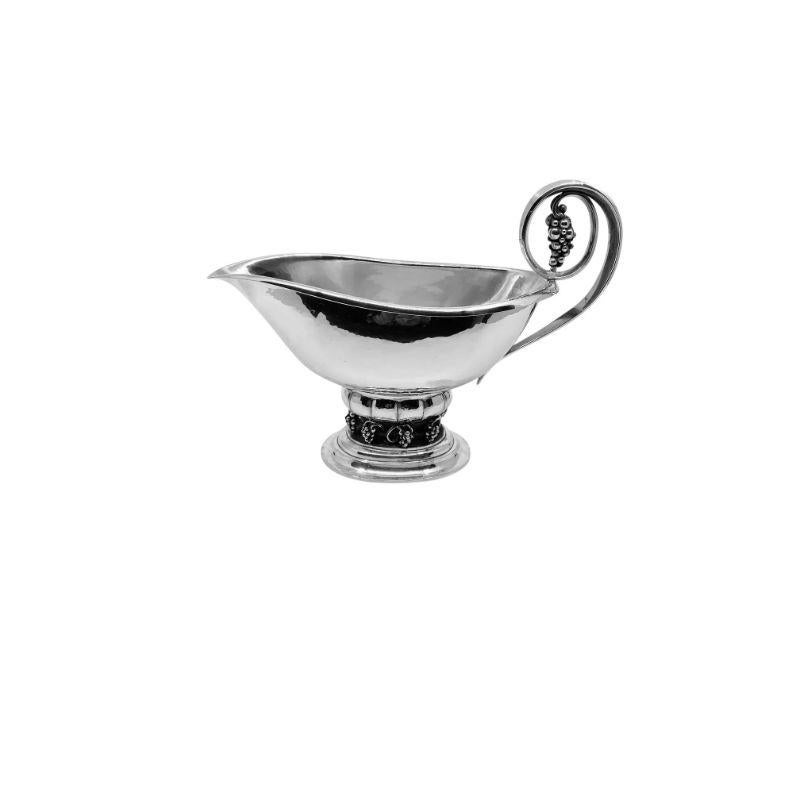 An extra-large Georg Jensen grape design sauce boat, design #296 by Georg Jensen in 1924. Oval base with eight grape bunches on the vine pedestal that holds the sauce boat. The elevated handle with one large bunch of grapes.

Additional