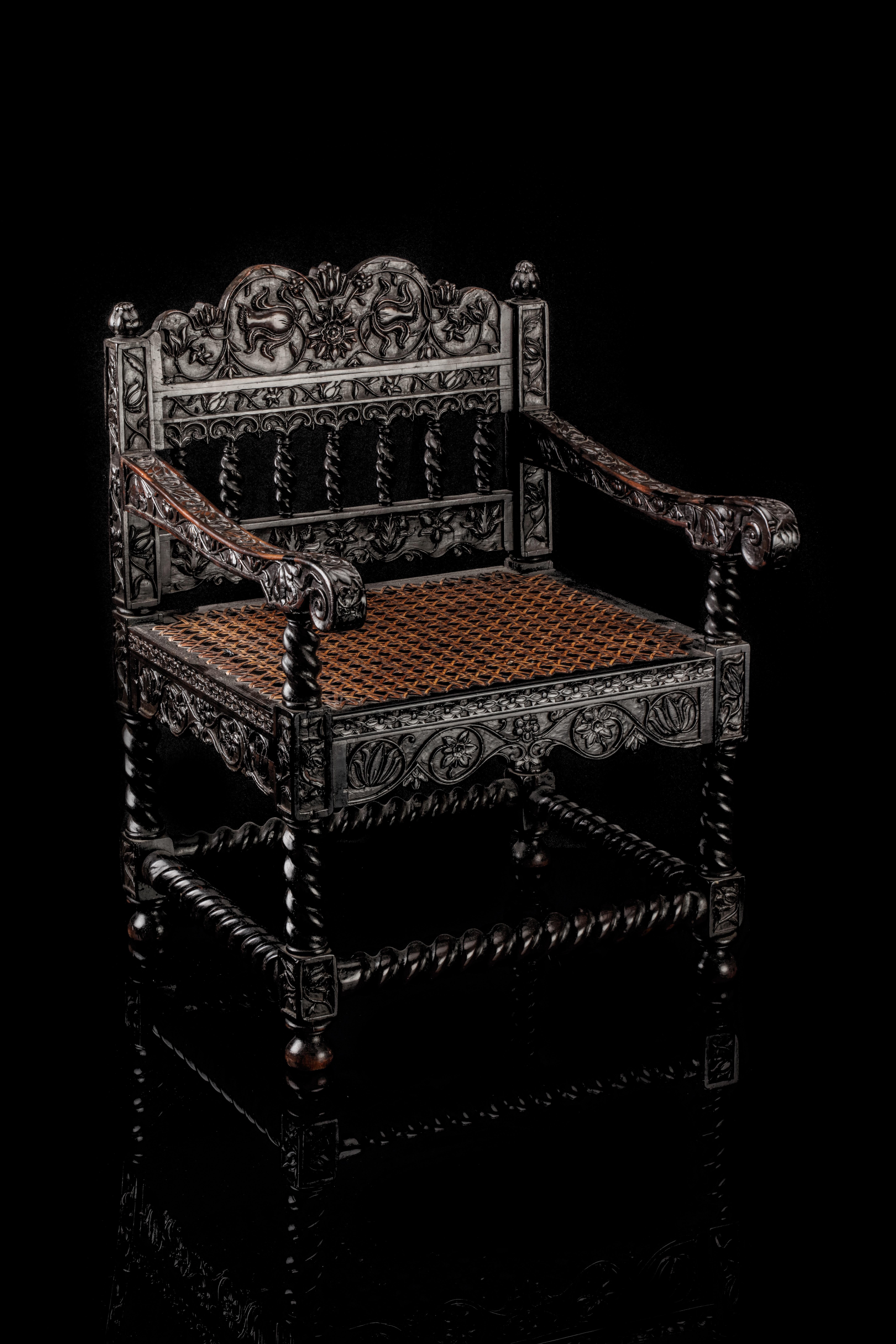 Probably Sri Lanka, 2nd half 17th century

H. 55 x W. 40.5 x D. 40.5 cm
Seat height 27.5 cm

The chair is overall densely carved with a scrolling flower motif on four connected turned legs and bun feet, with cane seating. Often, normal-sized