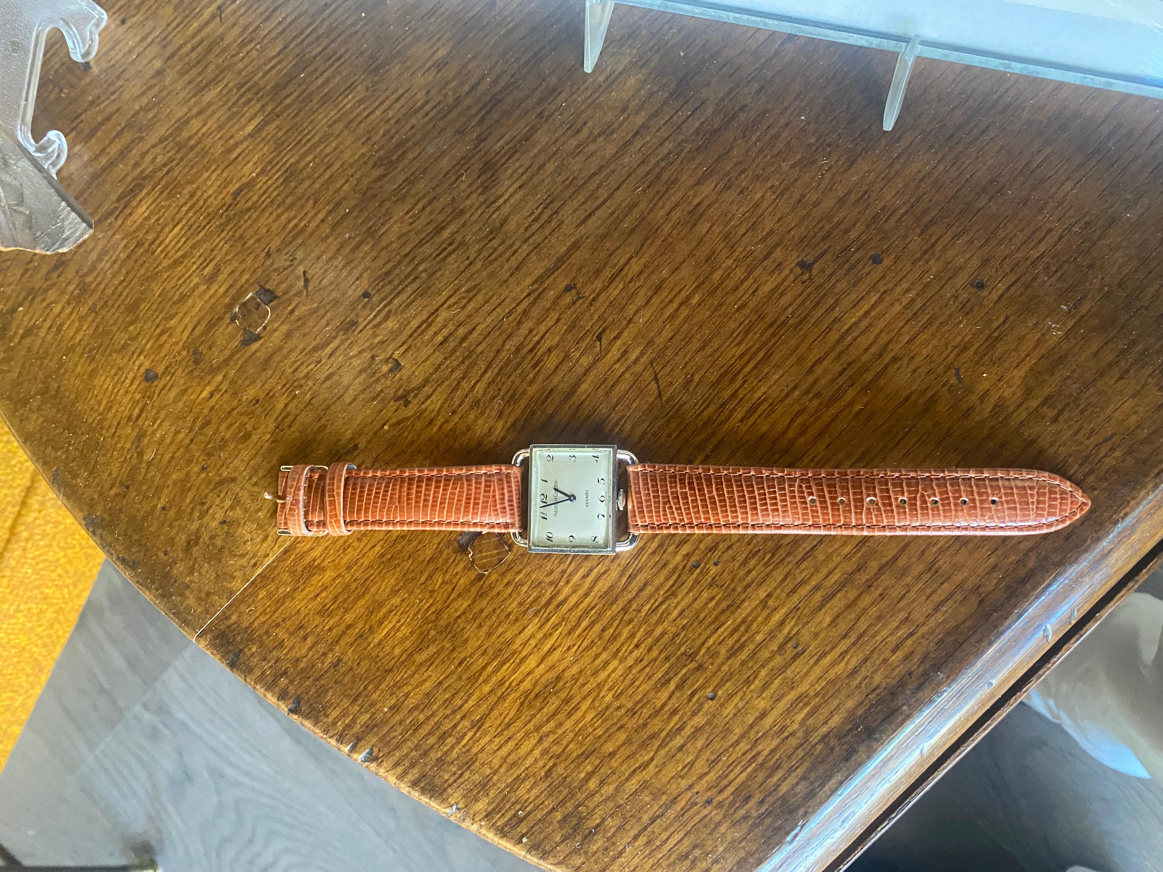 Eine Hermes-Uhr, 
Handaufzug mit quadratischem Edelstahlzifferblatt, braunem, geprägtem Hadley-Roma-Lederband und hellgoldener Dornschließe. 
Gestempelt: Jaeger-LeCoultre für Hermes.