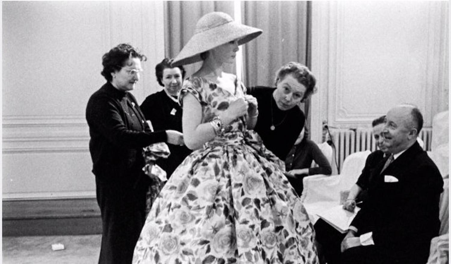 Ligne Libre Collection Spring-Summer 1957
Paris - France

A printed chiné taffeta ball gown with large blooming roses and foliage in salmon, light brown and yellow green tones on ivory background. Sleeveless and V neck bodice with pleated effect
