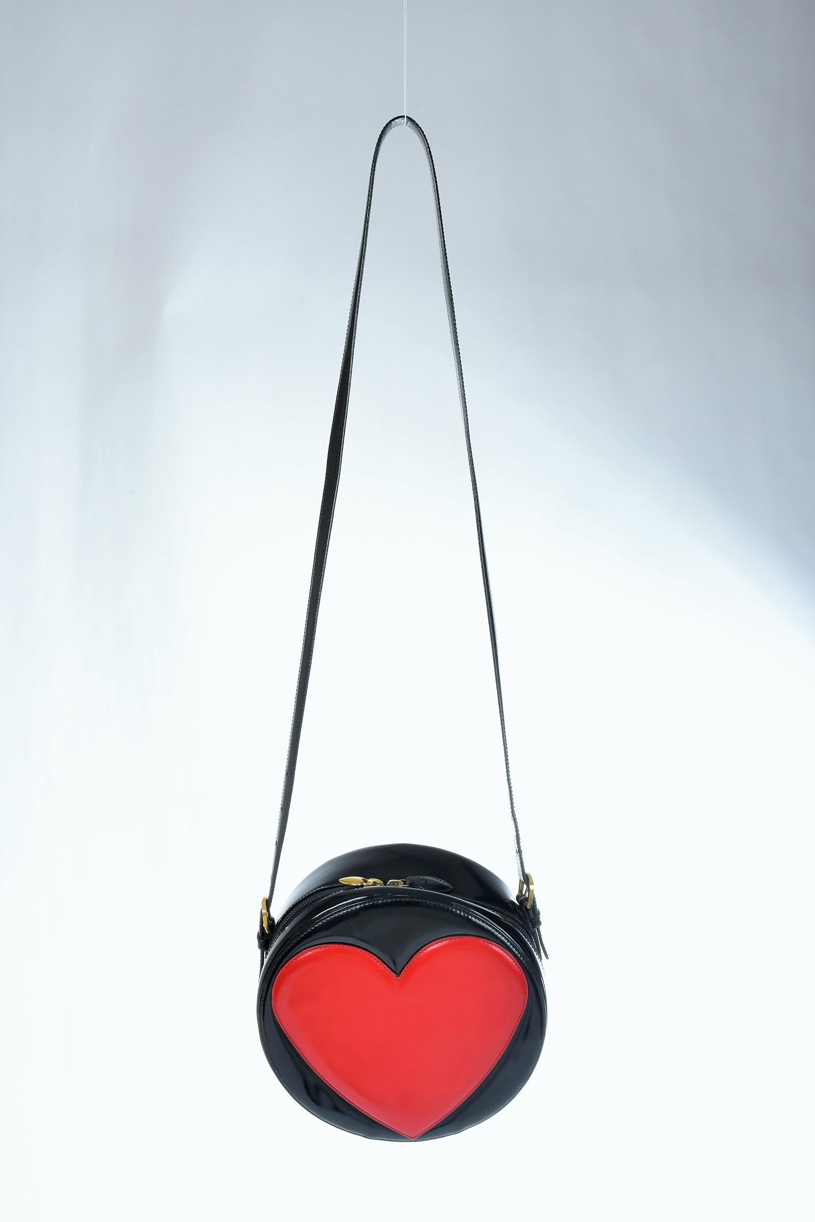Circa 1990

Italy

Rare small tambourine bag by Franco Moschino (1950-1994) with the famous heart applied in reference to Pop Culture and dating from the early 1990s. Black varnished vinyl with zip closure on the side with a brass heart puller.