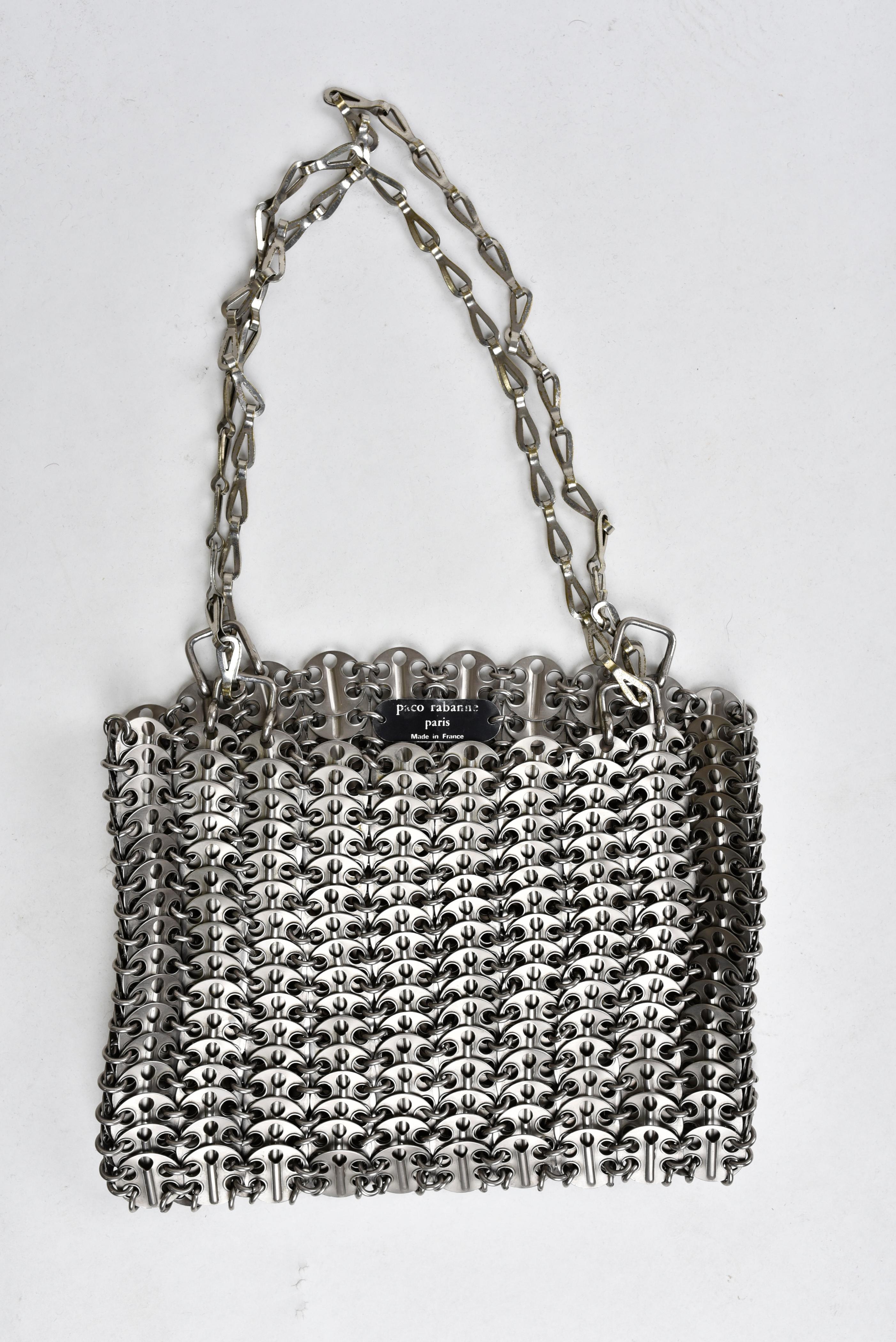 Circa 1969

France

Iconic shoulder bag by Paco Rabanne dating from the late 1960s. Besace structure in perforated metal discs maintained by rings. Original sliding chain allowing the bag in hand or shoulder. Black metal claw indicating Paco Rabanne
