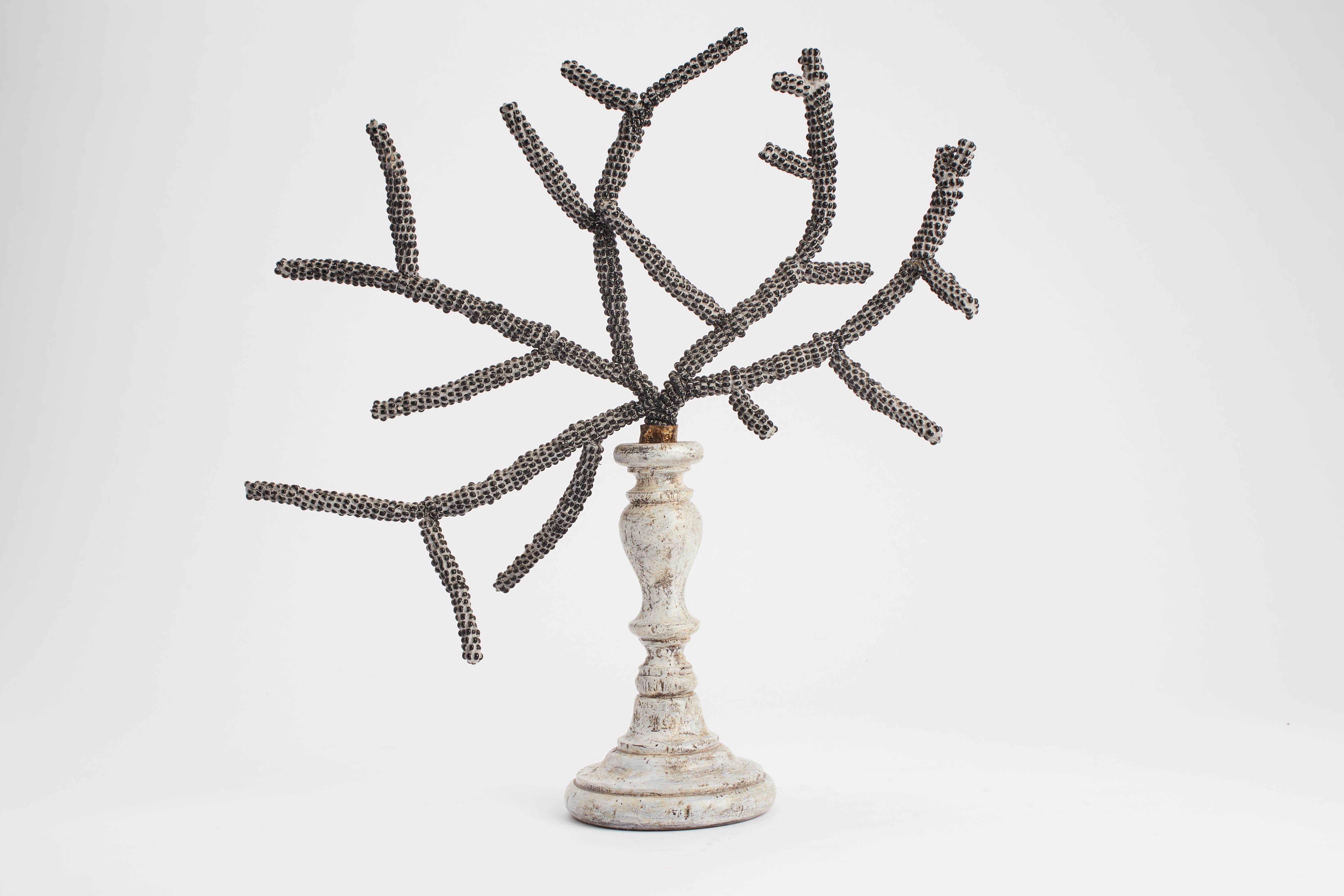 The base is wheel turned wood, white laquered painted. The branch is emulated by a metal rod covered by stucco and Murano glass, black beads. Italy circa 1780.