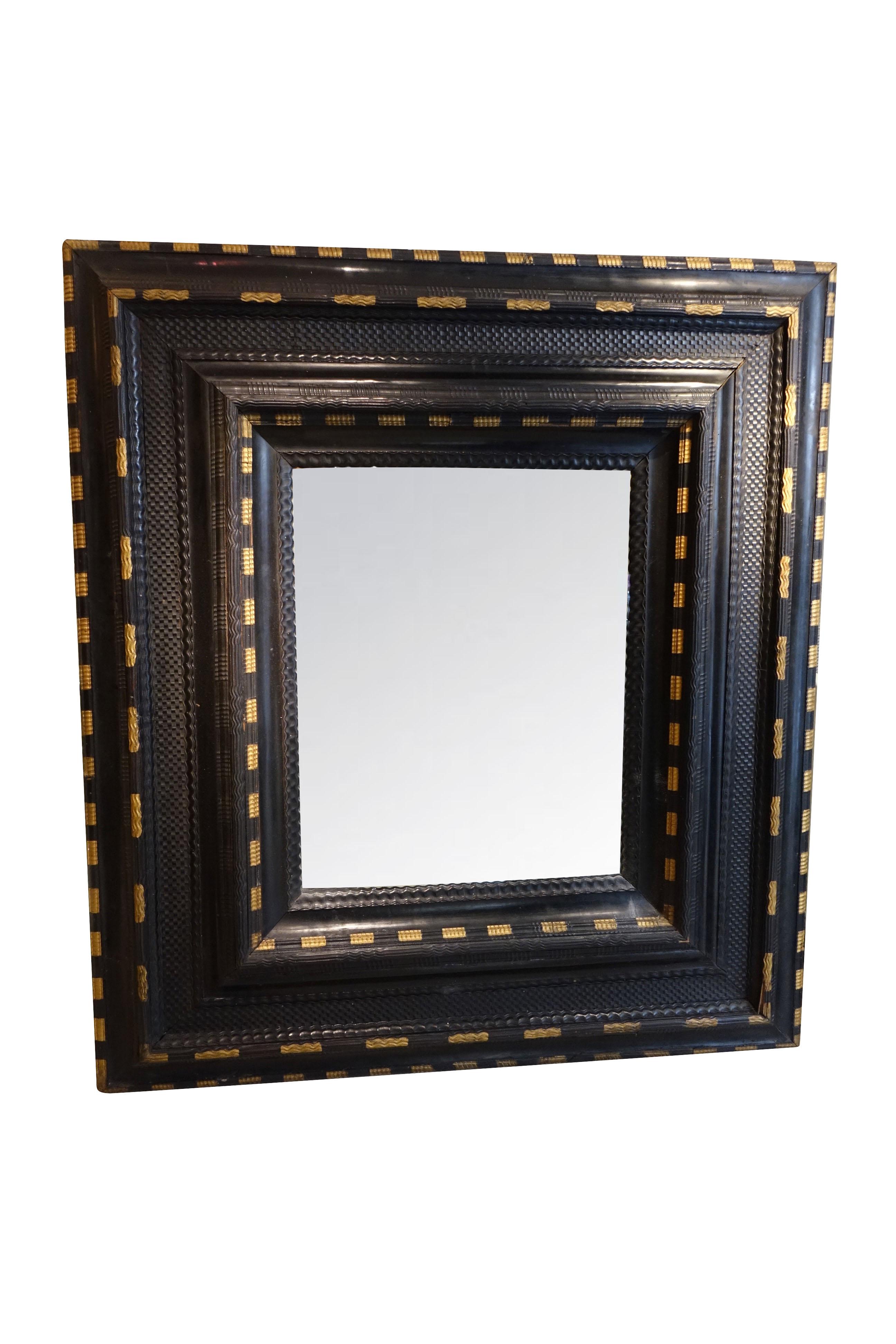 A large ebonized wood mirror with a wide framework decorated with doucines and mouldings with a guilloche pattern.
A original mercury glass in the center, gold-plated highlights on inside and outside of the mouldings.
Parquet work on the