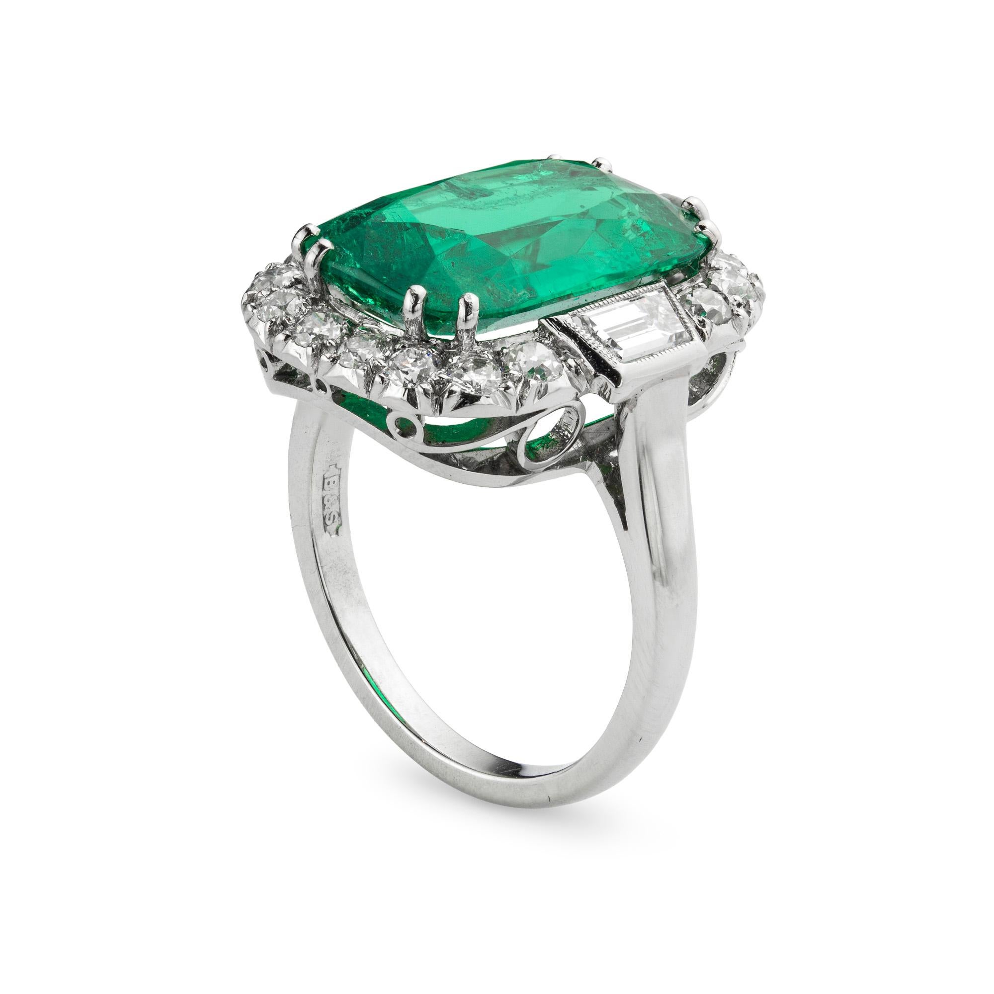 Un importante anello con smeraldo e diamanti a grappolo, con uno smeraldo taglio cuscino del peso di 5,91 carati accompagnato da un rapporto GCS che ne attesta l'origine colombiana, incastonato in una cornice formata da due diamanti taglio trapezio