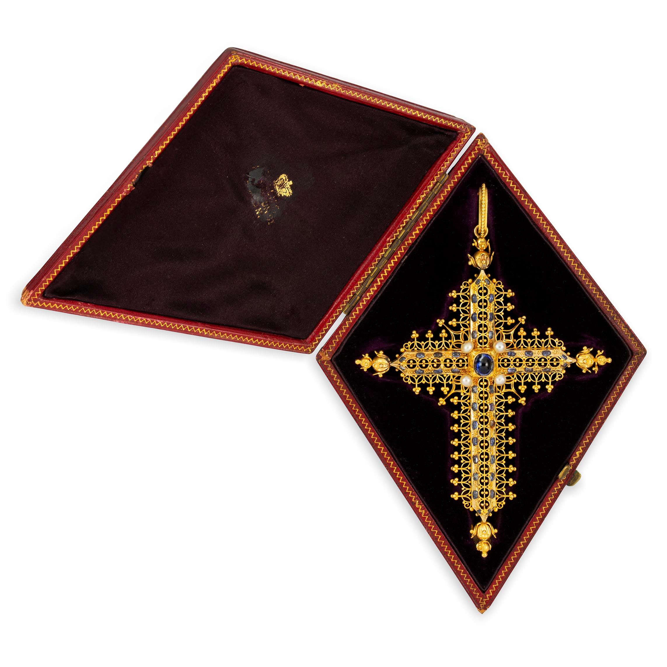 An Important gold and sapphire cross by Robert Phillips, the ornate gold cross set with a cabochon-cut sapphire and four pearls to the centre with further cabochon sapphires to the edge and gold bead and wirework decoration, circa 1865, gross weight