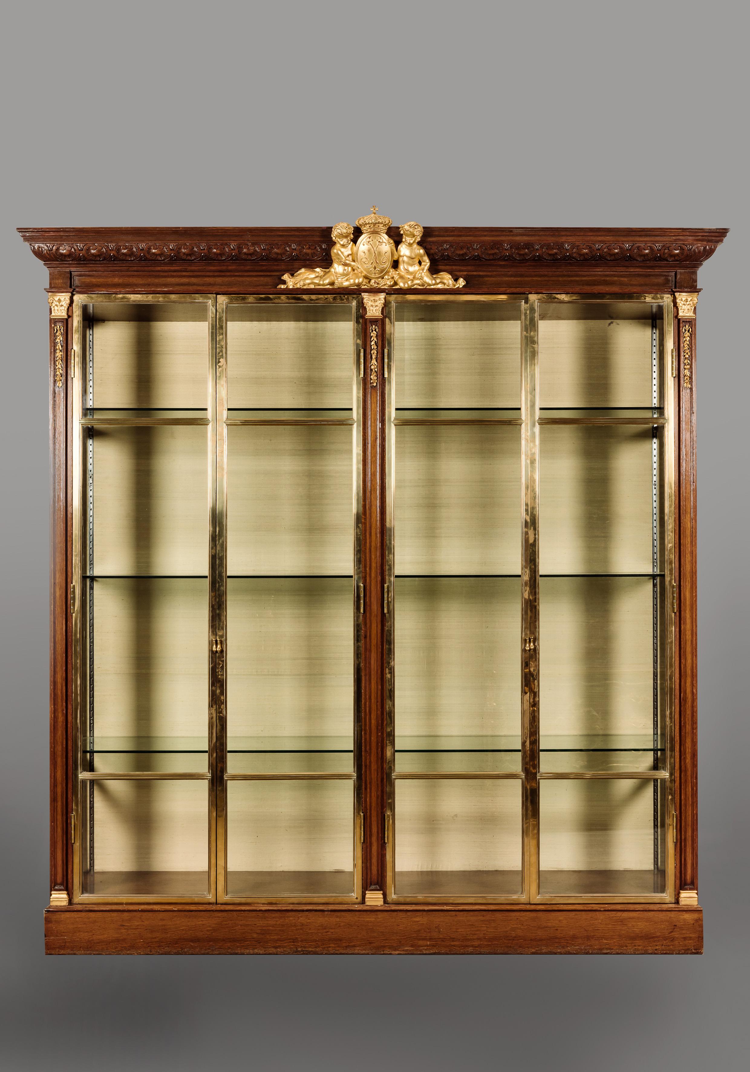 An important oak, giltwood and bronze four door Grande Vitrine.

French, circa 1870. 

An important oak, giltwood and bronze four door 'Grande Vitrine'. The projecting cornice finely carved with a frieze of linked coquillage centred by a