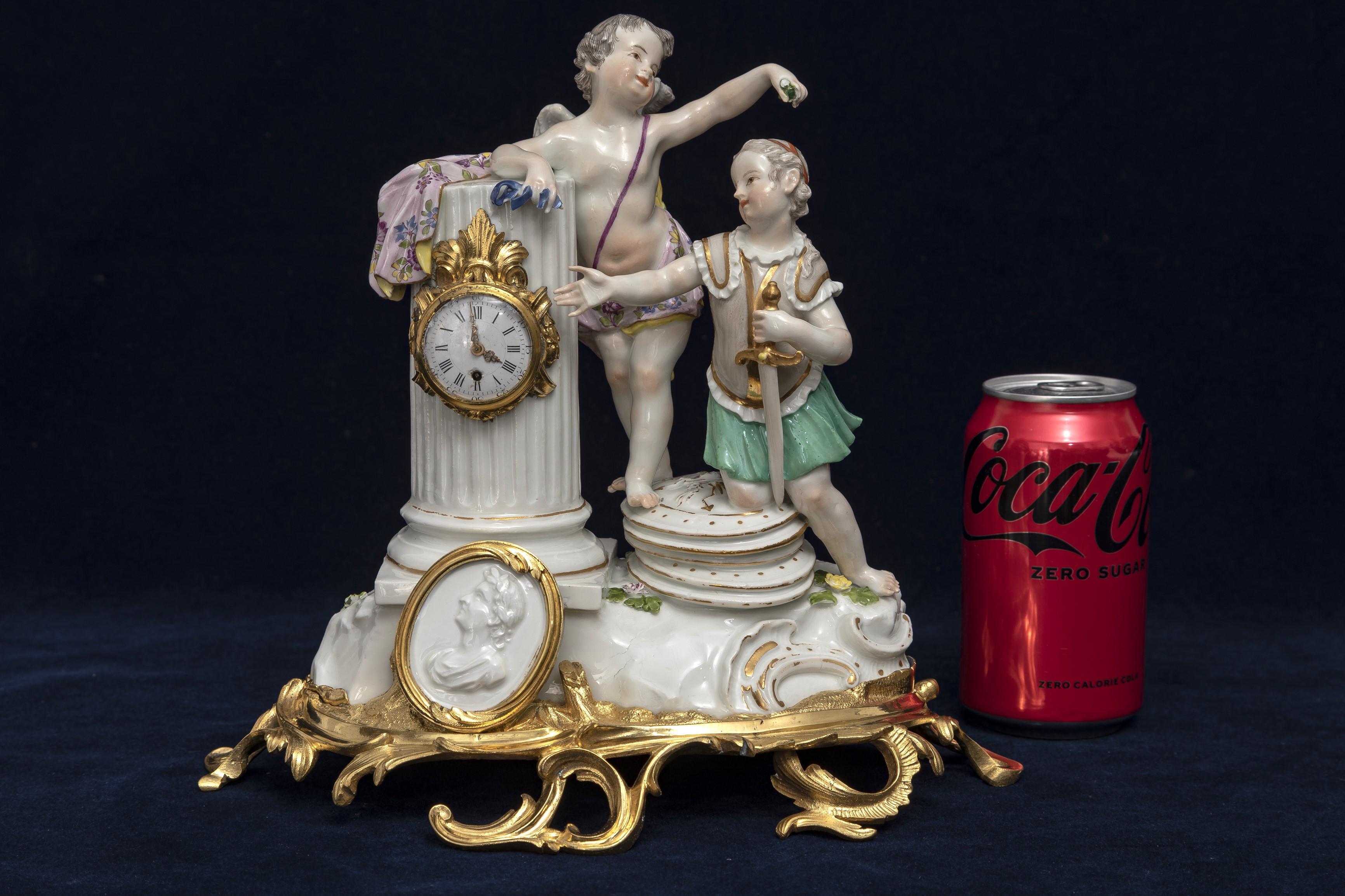 An Incredible and Quite Important 18th Century Ormolu Mounted Meissen Porcelain Putti Clock Grouping.  The composition is enriched with two putti positioned atop a porcelain naturalistic mound. One putti, clad in military attire, leans his knee