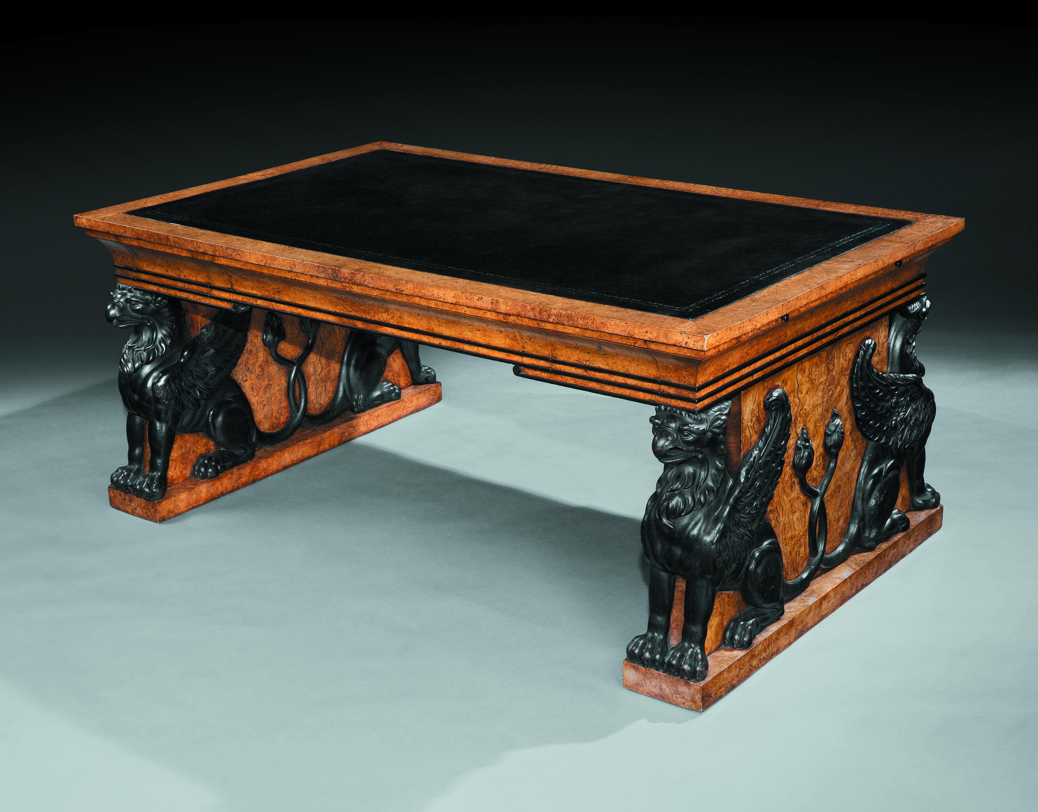 An Important Regency Burr Oak Writing Table 
The rectangular top with a thick band of burr oak and black leather writing surface with two draw leaf ends, above six opposing well shaped drawers, with ebonized mouldings, resting on superbly carved