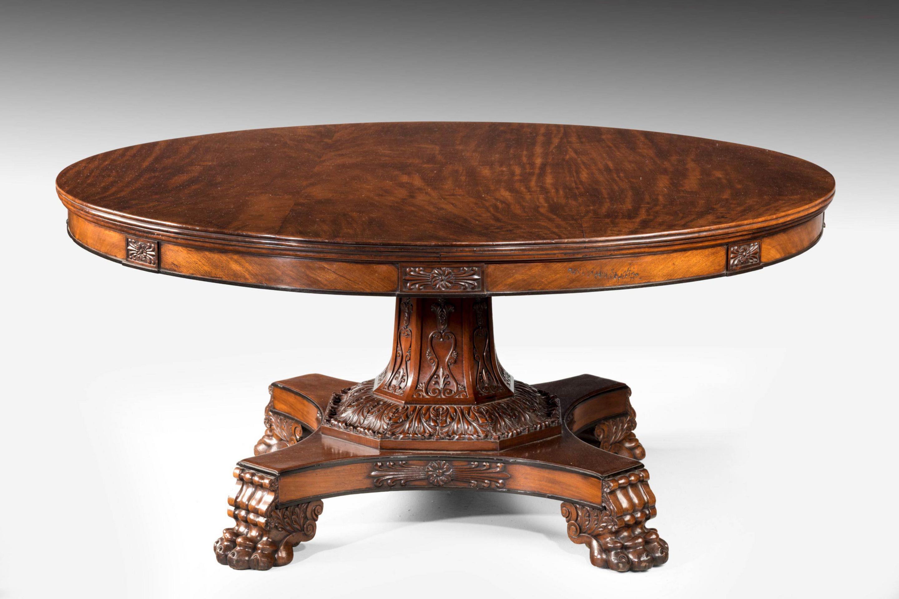 A Large Scottish Regency Mahogany Centre Table

The circular figured mahogany top with a reeded edge, above a figured mahogany frieze with carved rosettes, the hexagonal stem of the base carved with anthemions, resting on bold acanthus leaves, the