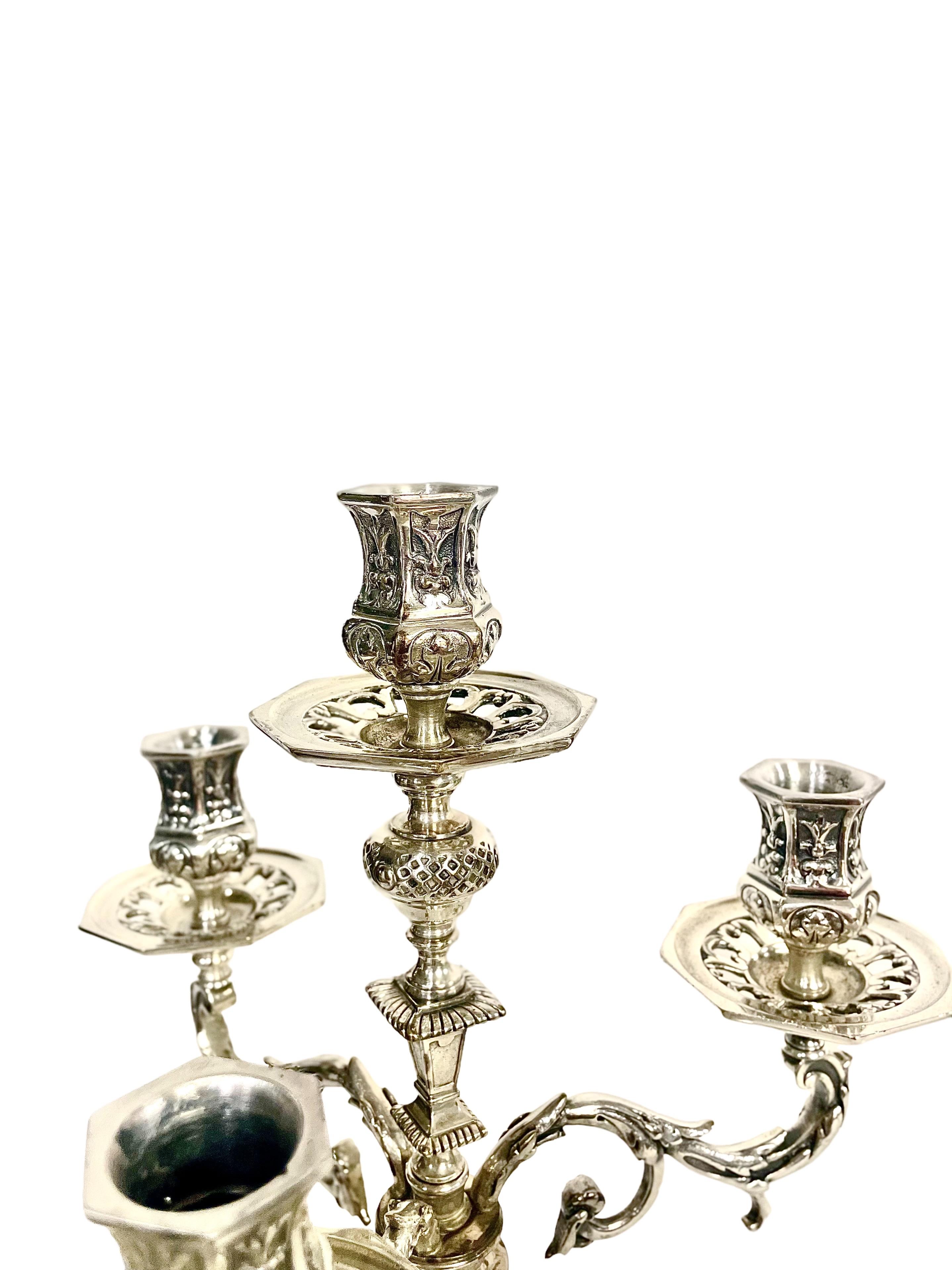 An imposing pair of tall, silver-plated bronze four-light candelabra in the late 19th century Renaissance style. Each piece is very ornately engraved, with intricate palmettes, scrolls and 'mascaron' carved faces adorning its heavy base and lower