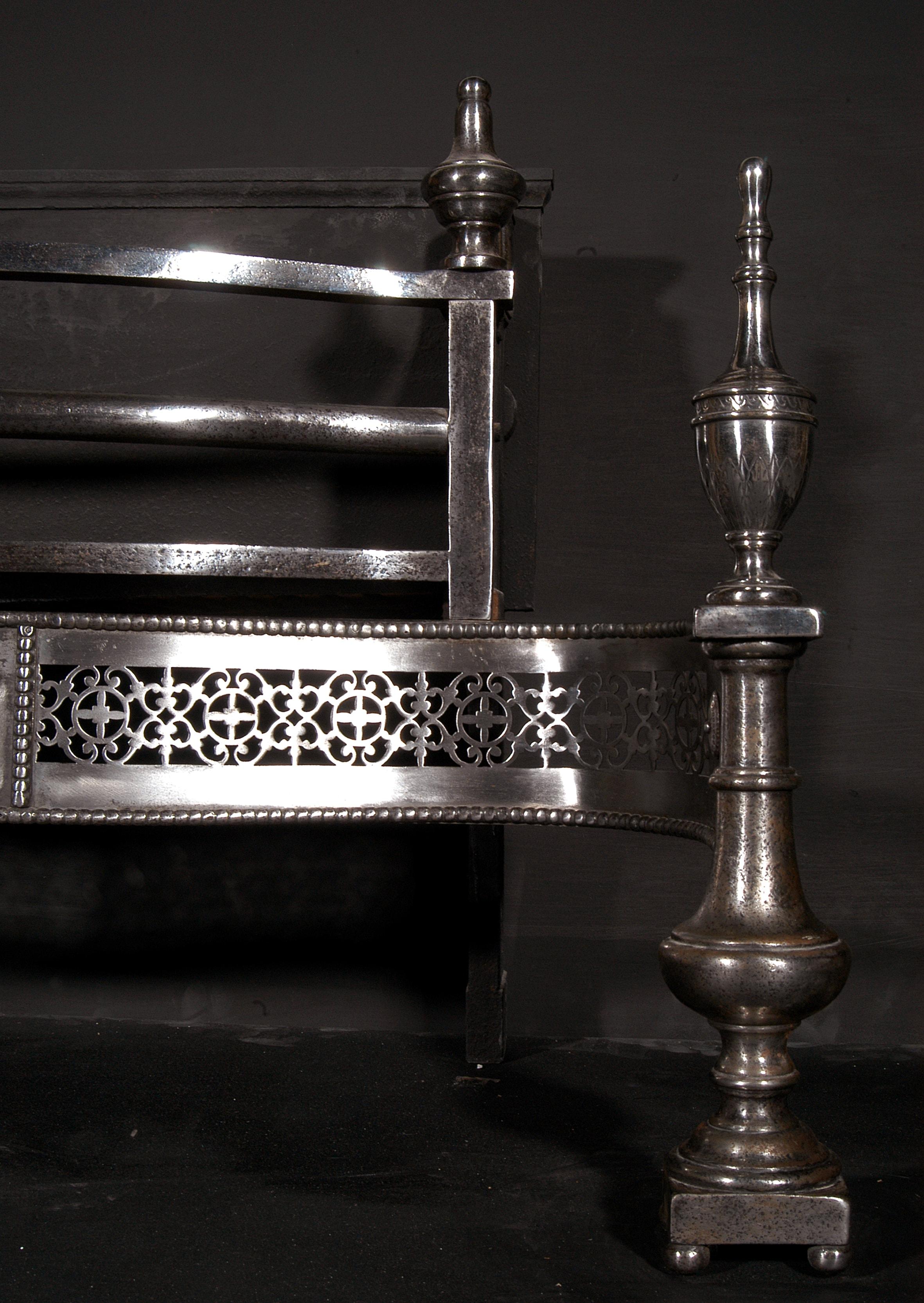 An early 19th century English polished steel firebasket. The ornately pierced fret and centre with engraved pateras, cylindrical dogs on ball feet, surmounted by engraved finials. A large and imposing piece.

Width At Front:	1125 mm      	44