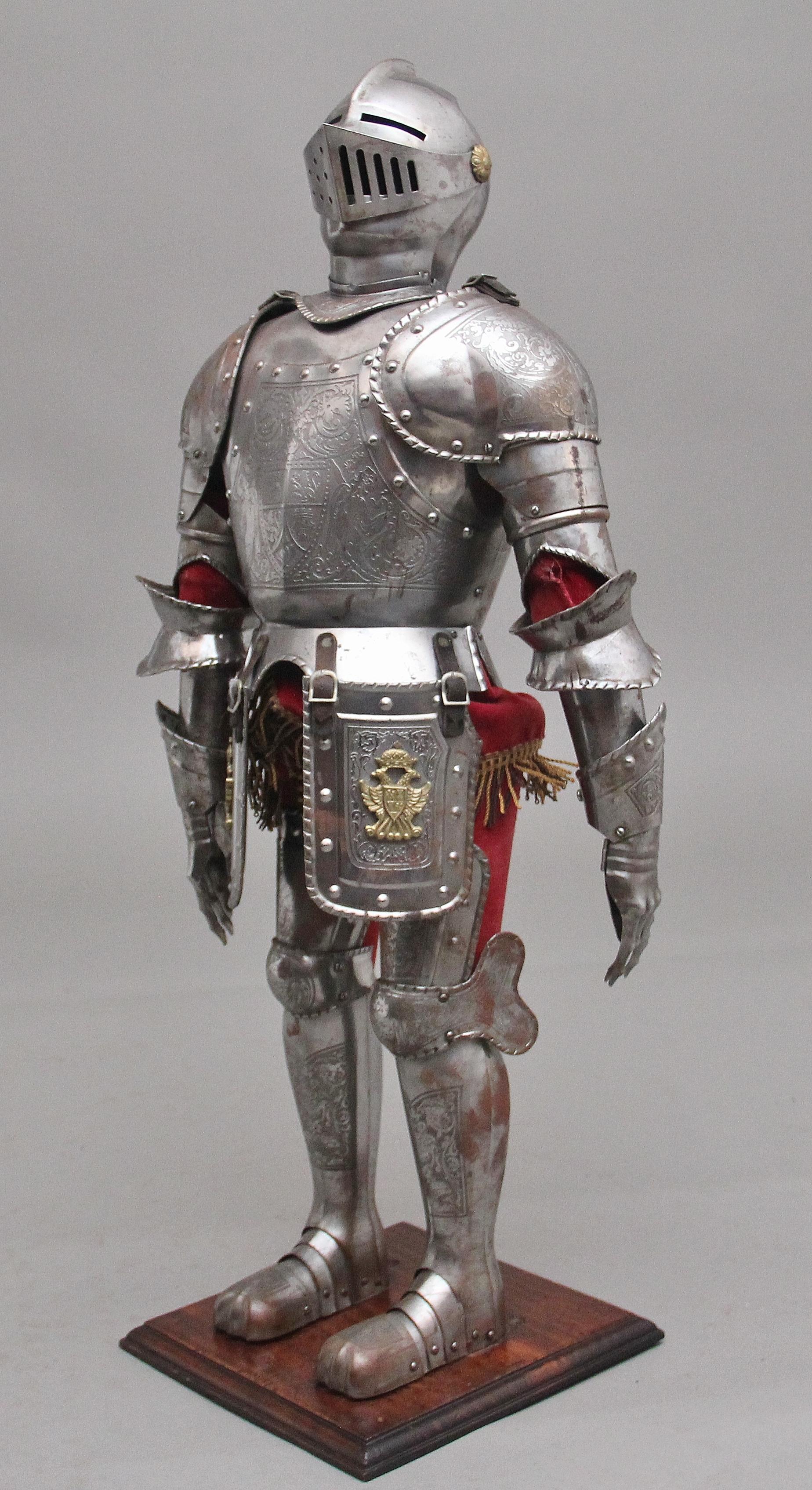 An impressive early 20th miniature suit of armour in the 16th century style, possibly German, the helmet is adjustable and has gold coloured patraes either side, the suit of armour has detailed engraving throughout and includes gold coloured coat of