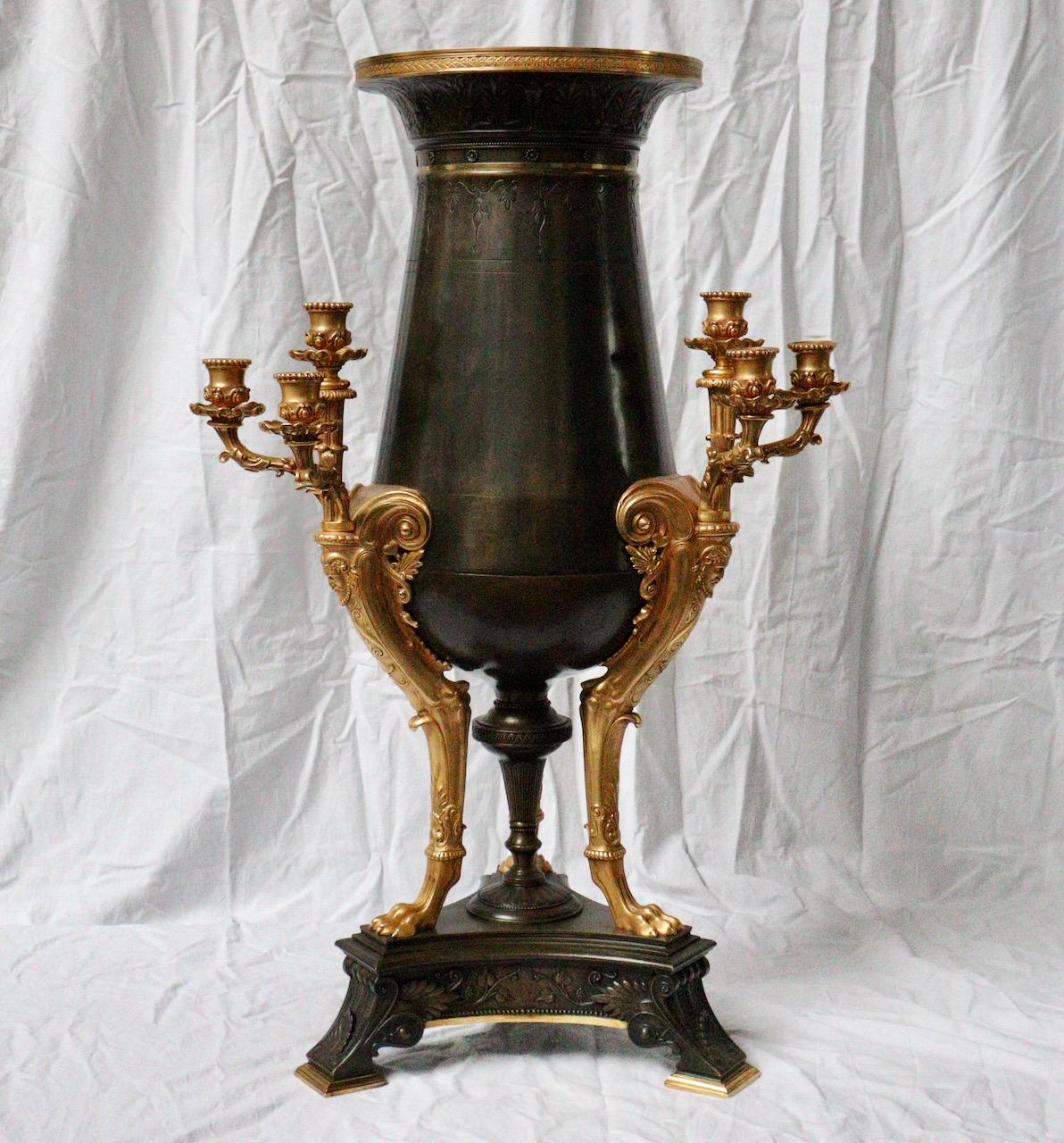 An impressive French 19th century Neo-Greek style bronze nine-lights center piece

In patinated and gilt bronze, engraved on the body of foliage and rings, the collar decorated with a frieze of palms in bas-relief. It is held by a tripod base