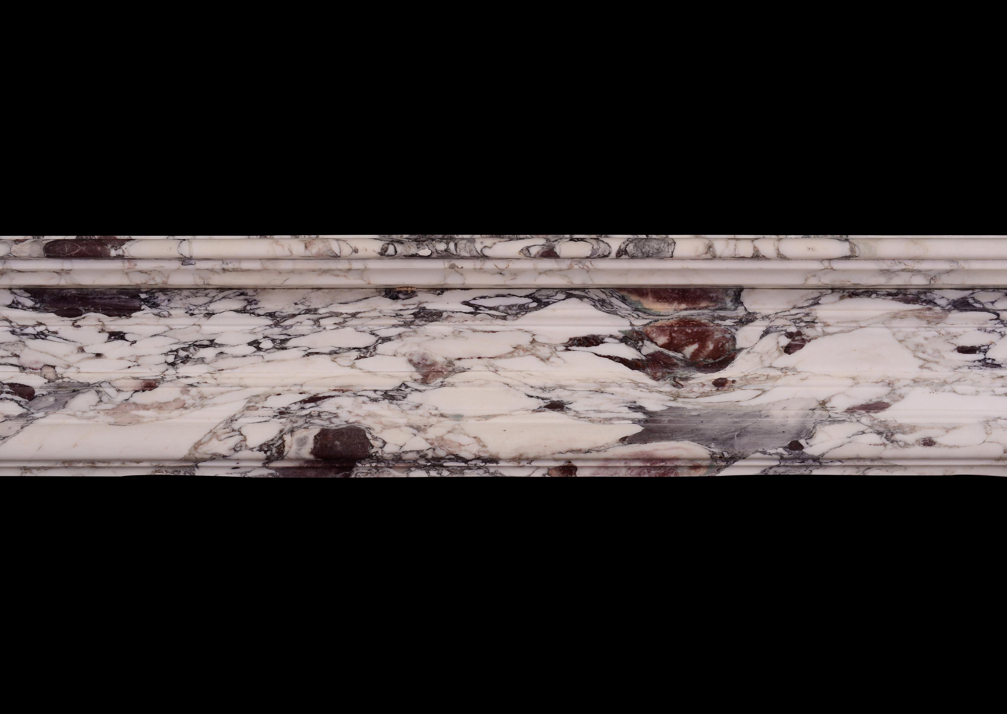 Une impressionnante cheminée de style Louis XIV en marbre de Violette. Les jambages cannelés et lambrissés sont surmontés d'une frise cintrée et lambrissée. Etagère moulurée au-dessus. Une cheminée très profonde en marbre. Français, 19e