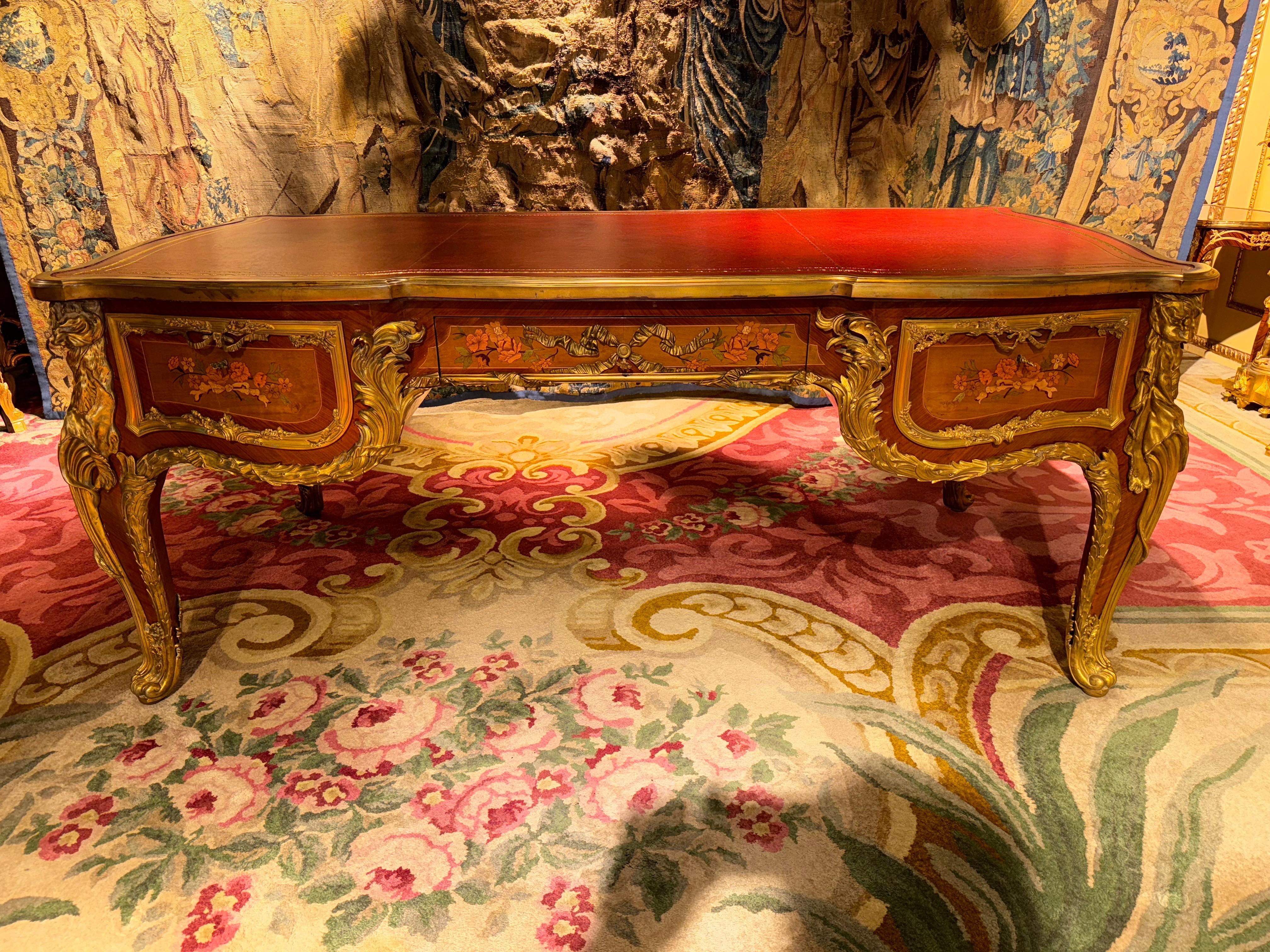 AN IMPRESSIVE LOUIS XV STYLE BUREAU PLAT /DESCRIPTION - AFTER THE BUREAU DU ROI AT VERSAILLES BY J.-F. OEBEN AND J.-H. RIESENER

The rectangular top, with the outline of an arc-en-arbalète, is fitted with an embossed leather writing surface and is