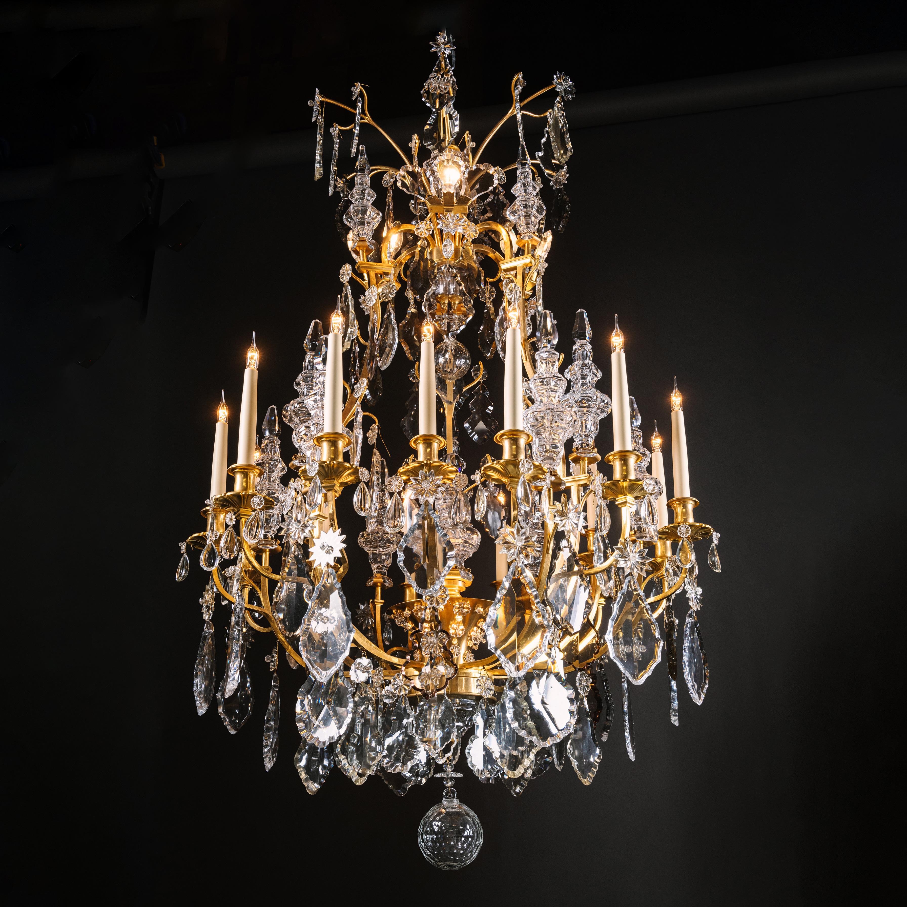 An impressive Louis XV style gilt-bronze and cut-crystal and moulded-glass fifteen-light chandelier. 

The corona with branches and three concealed bulbs. The cage frame issuing fifteen branches supporting baluster glass finials and terminating in