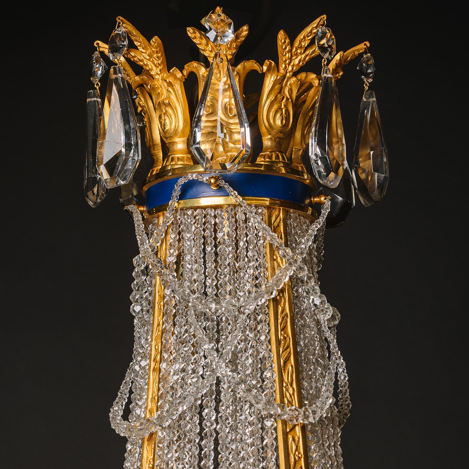 An Impressive Louis XVI Style Gilt-Bronze and Glass Tent and Bag Eight-Light Chandelier. 

This fine chandelier has a gilt-bronze acanthus cast corona hung with octagonal flatbacks and faceted pear-shaped drops above a blue enamel band from which