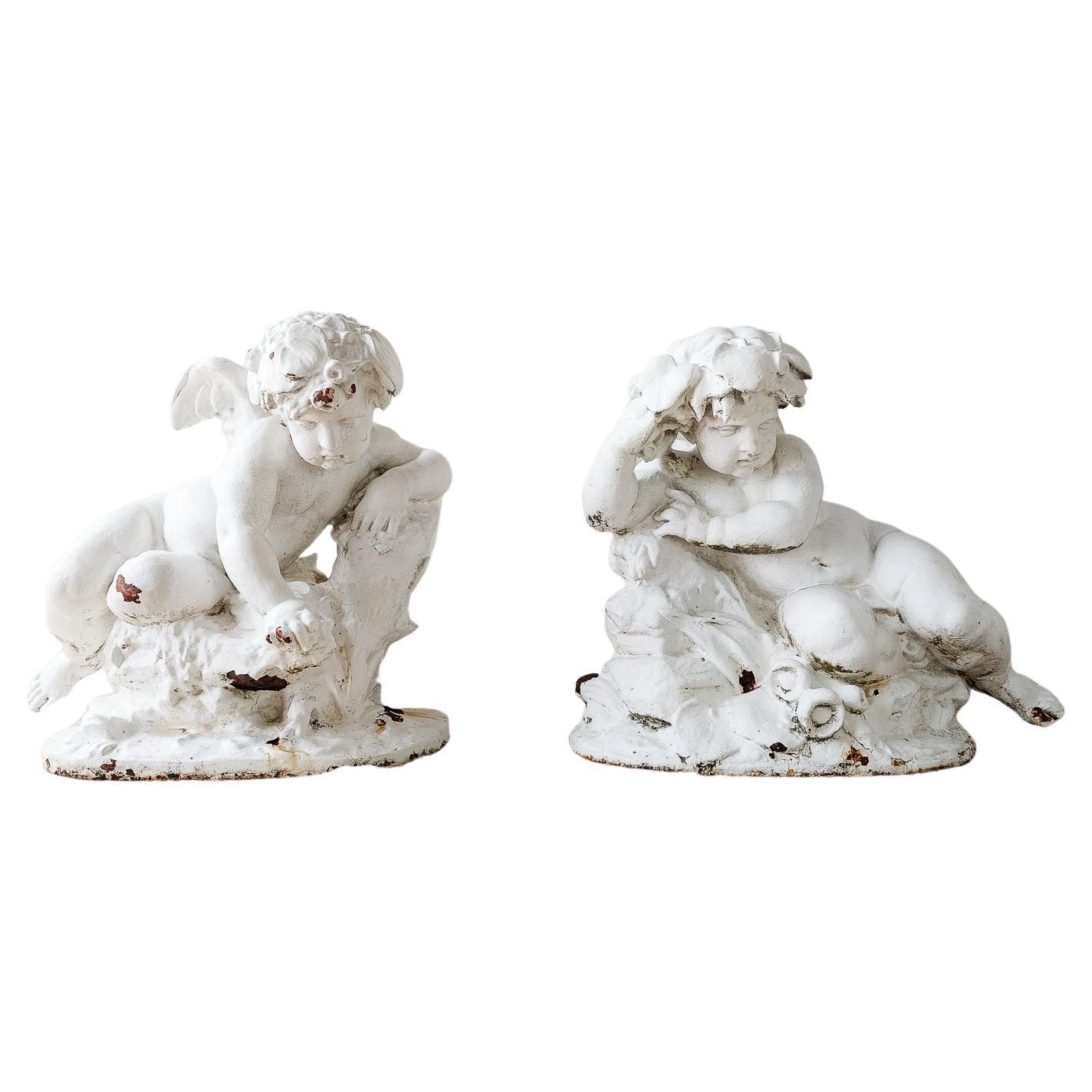An impressive pair of monumental sized cast iron putti. These super large sculptures are made in the manner of the 18th century. The cast iron has it's original white patina, which shows wear with their age. The putti are in a reclining position,