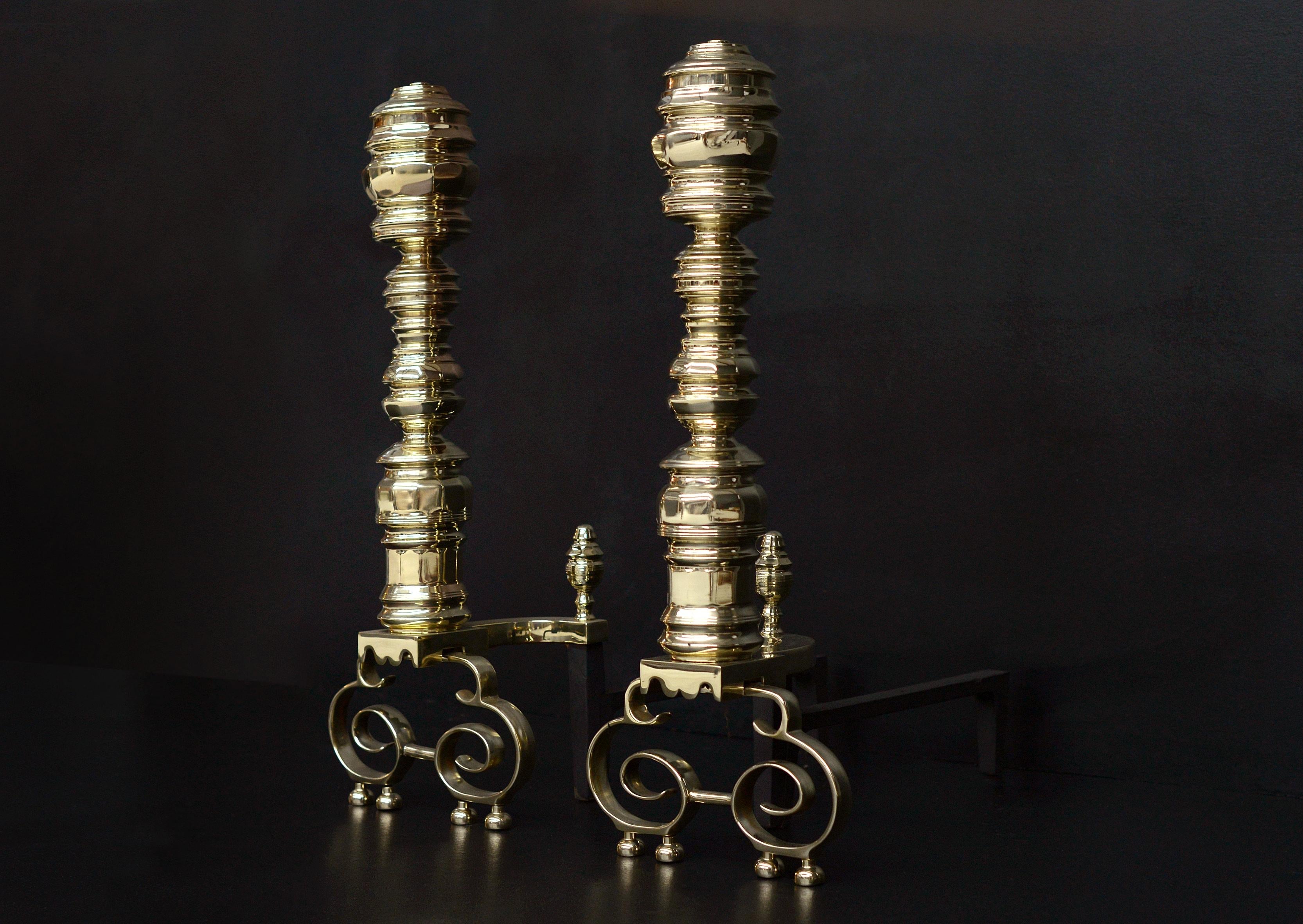 A large pair of English brass firedogs. The shaped bases surmounted by turned shafts with hexagonal shaped top. Matching finial behind to backbars. Late 19th century / early 20th century.

Measures: Height: 680 mm 26 ¾