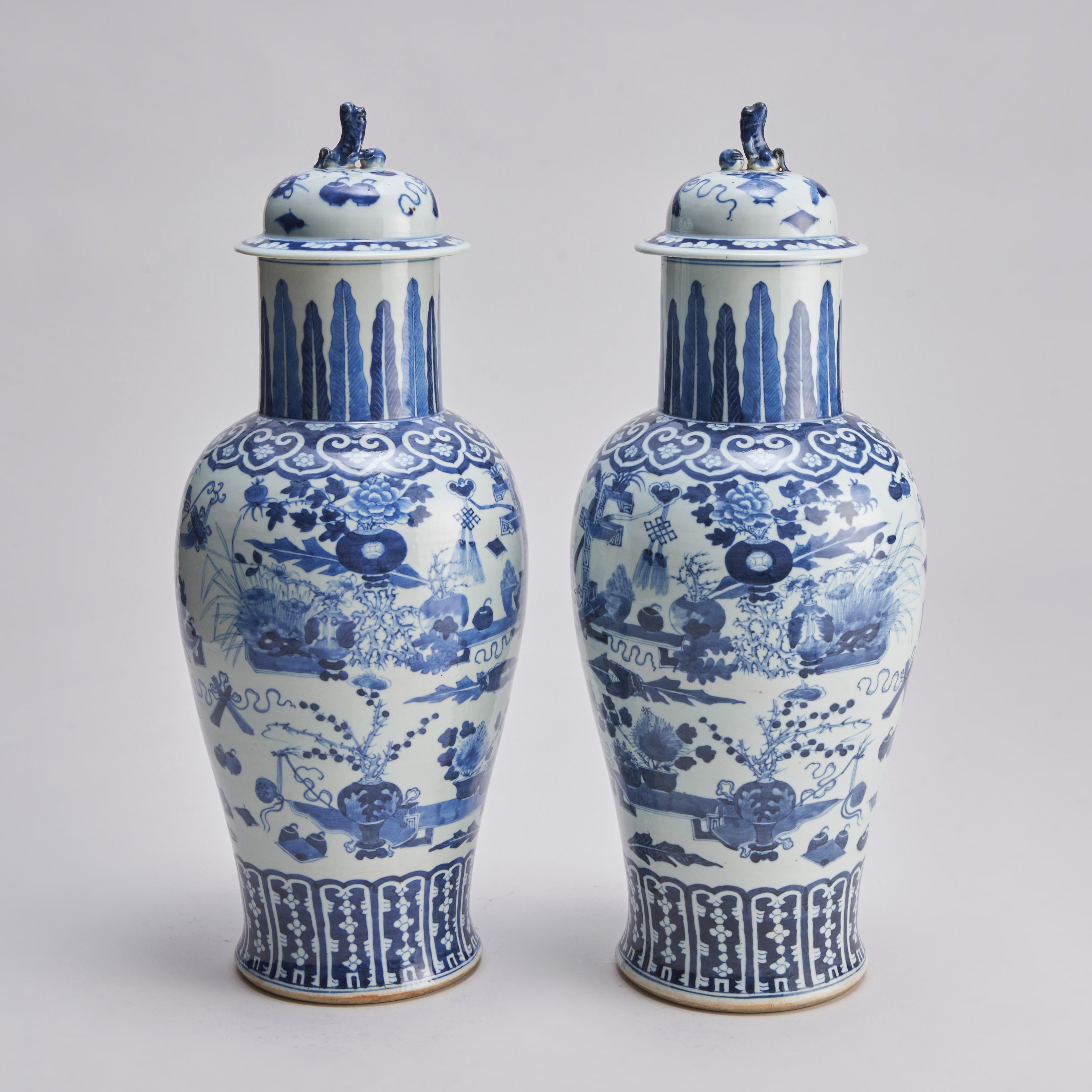 Une paire de vases chinois du XIXe siècle en bleu et blanc, finement décorés d'arrangements floraux et d'objets précieux d'érudition tels que des rouleaux, des vases, des arrangements floraux et des instruments d'écriture, ainsi qu'un Penzai (arbre