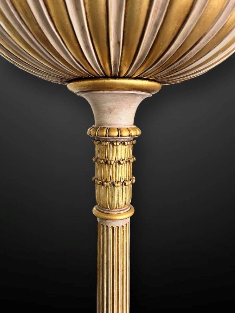 An impressive matching pair of 20th Century gilt and painted floor standing uplighters.

The pair of lamps feature a solid heavy set base with four paw feet with acanthus carving details, each set on a long fluted column with a large fluted bowl to