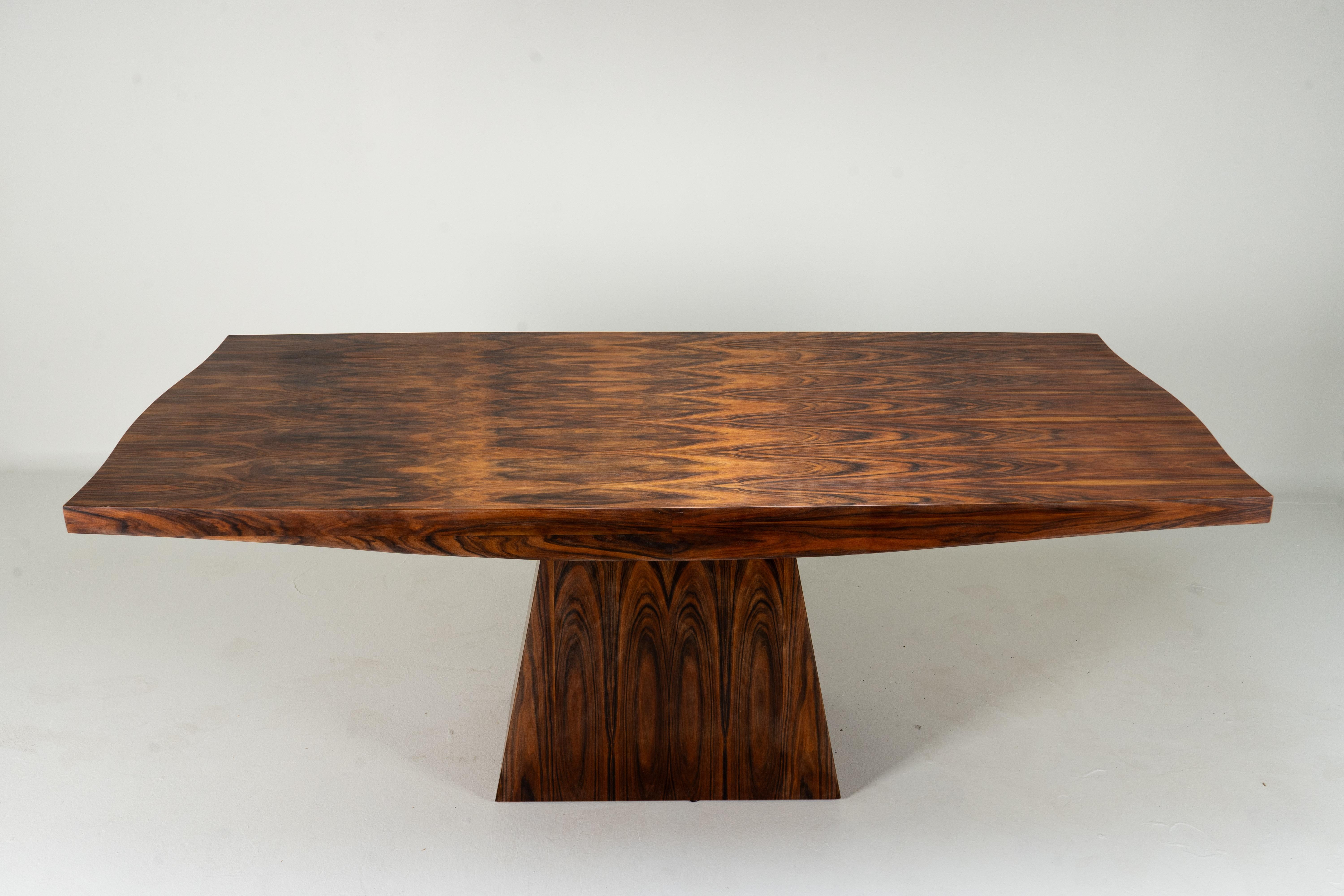Dieser elegante Esstisch ist ein außergewöhnliches Beispiel für die französische Handwerkskunst des Art Déco. Die Tischplatte aus Palisanderfurnier (Palisander) ist reichhaltig gemasert und mit einem kühnen, trapezförmigen Sockel versehen. Der