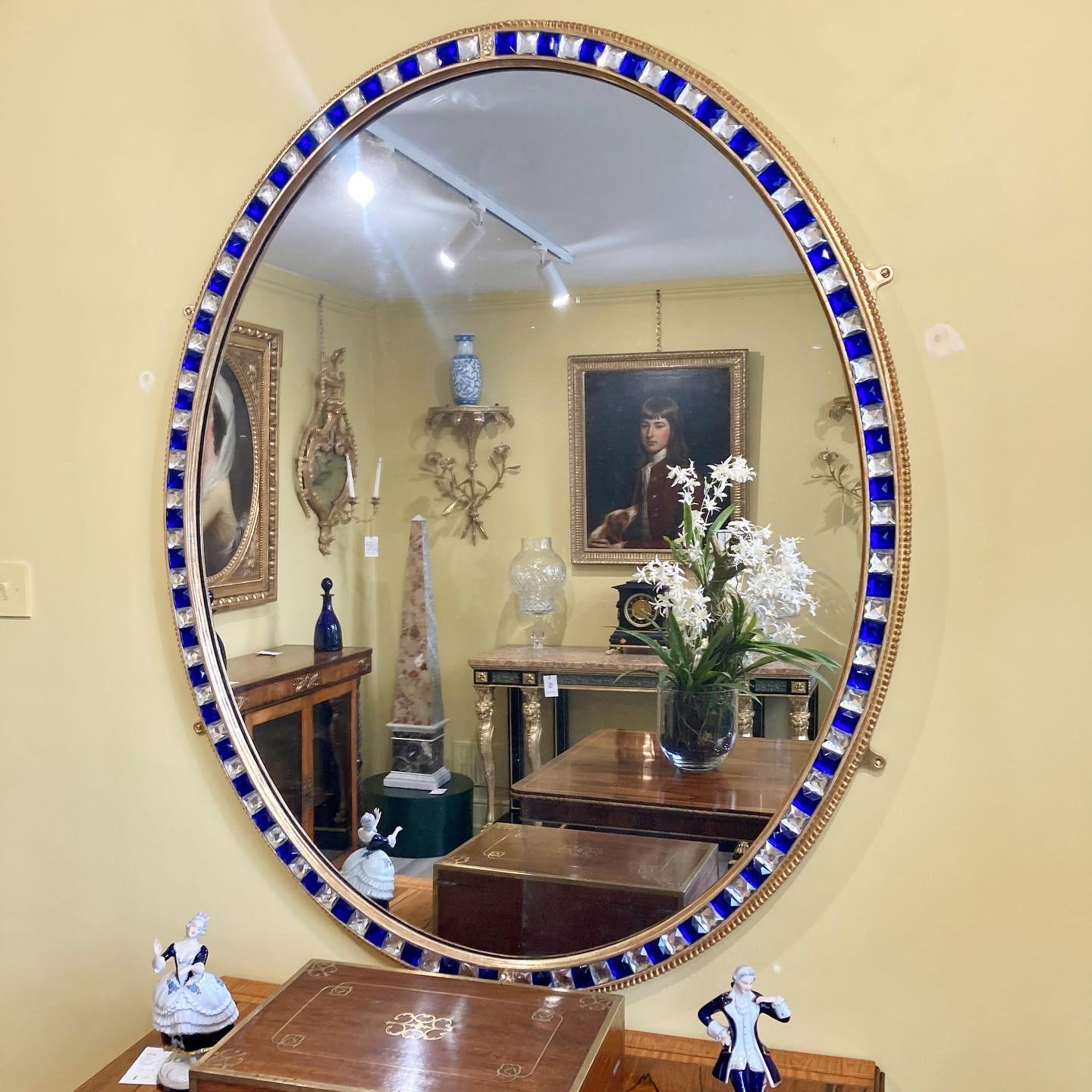 A magnificent 19th Century oval mirror of large scale with giltwood border inset with clear and blue glass cabochons - the cut glass decoration in the style of the renowned Waterford glasshouse.  The mirror with modern sparkling plate.