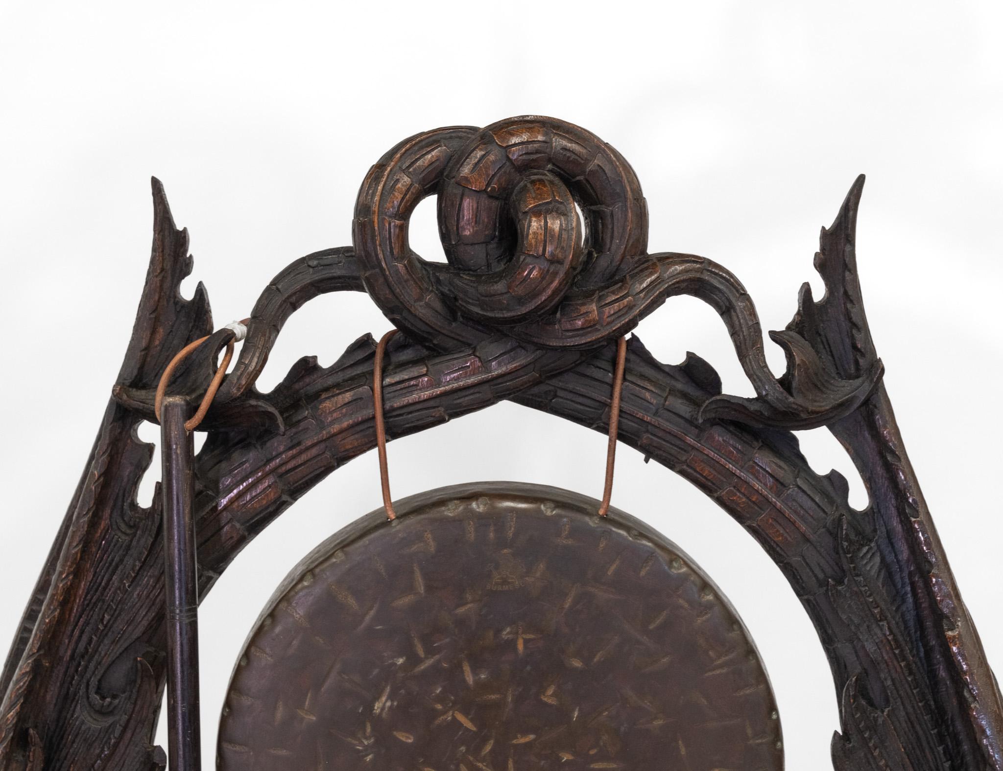 Gong de table et percuteur en chêne sculpté du XIXe siècle, d'une taille impressionnante, à poser sur le sol. Britannique - Circa 1880.

Le gong en bronze repose sur des bêtes mythiques entrelacées, sculptées à la main, et sur un socle en forme de